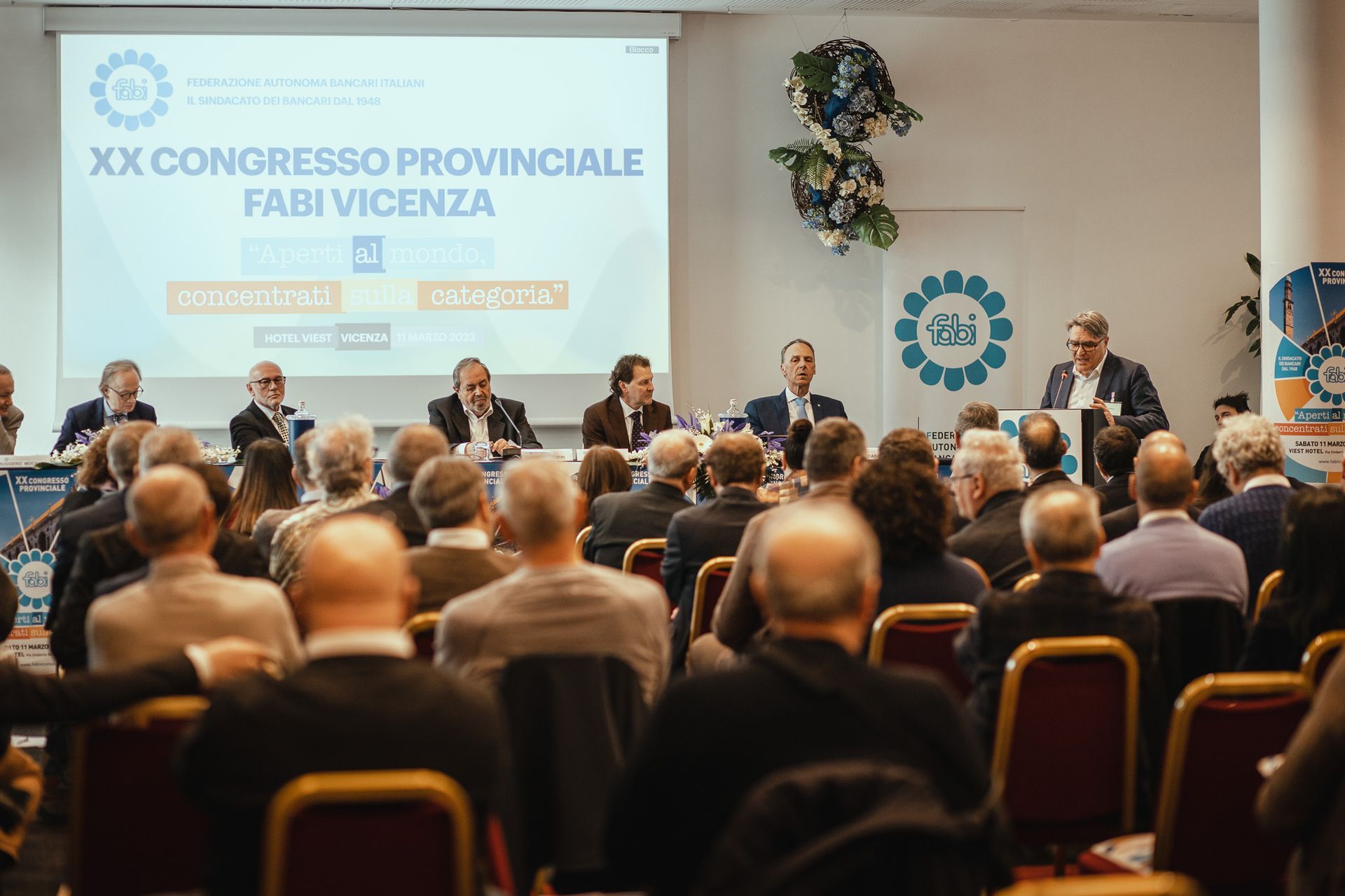 Un gruppo di persone è seduto in una sala conferenze e guarda una presentazione.