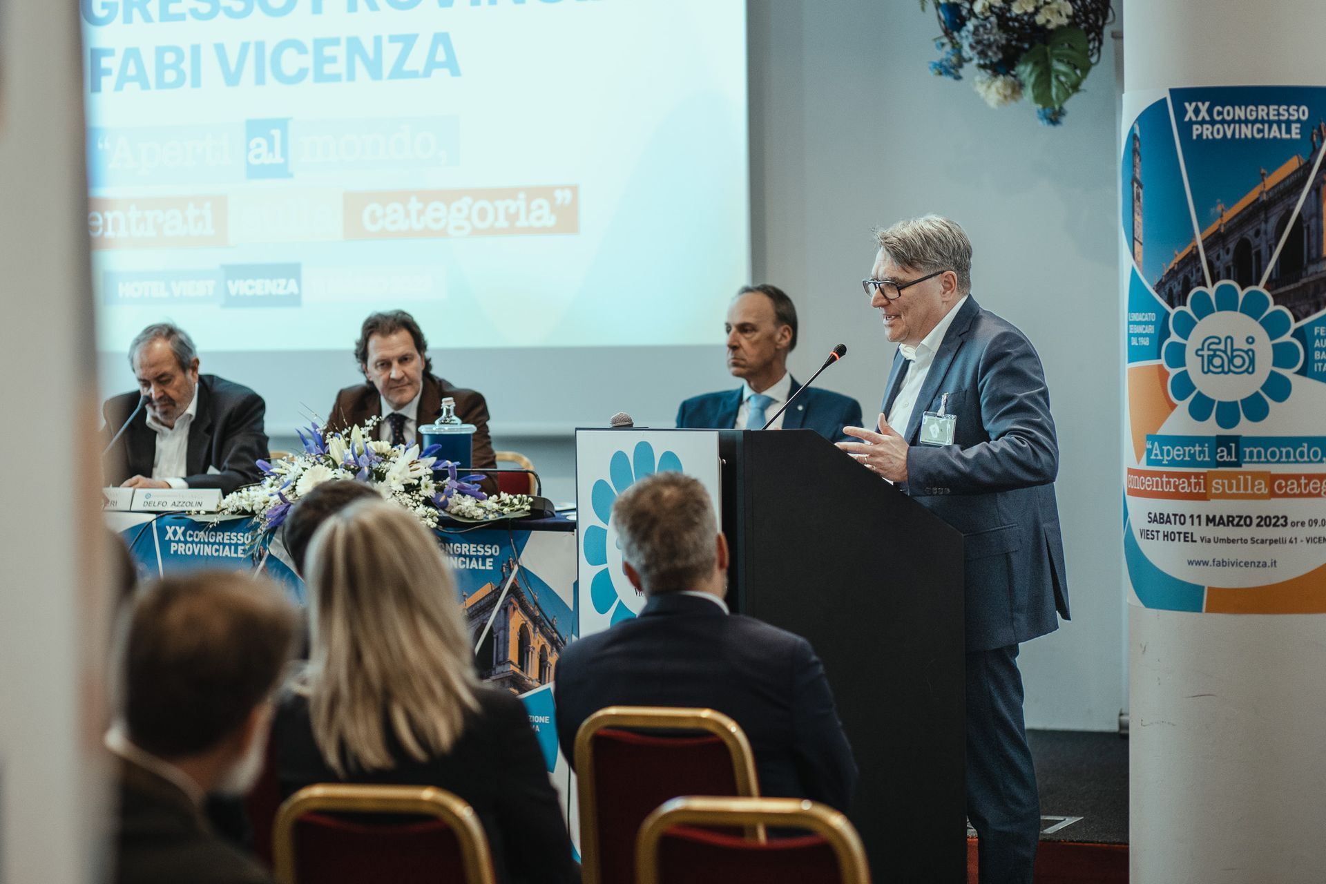 Un uomo è in piedi su un podio e fa una presentazione a un gruppo di persone.