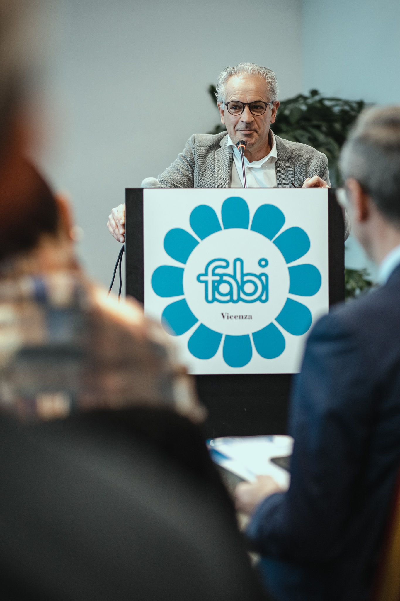 Un uomo è in piedi su un podio e tiene un discorso davanti a un gruppo di persone.