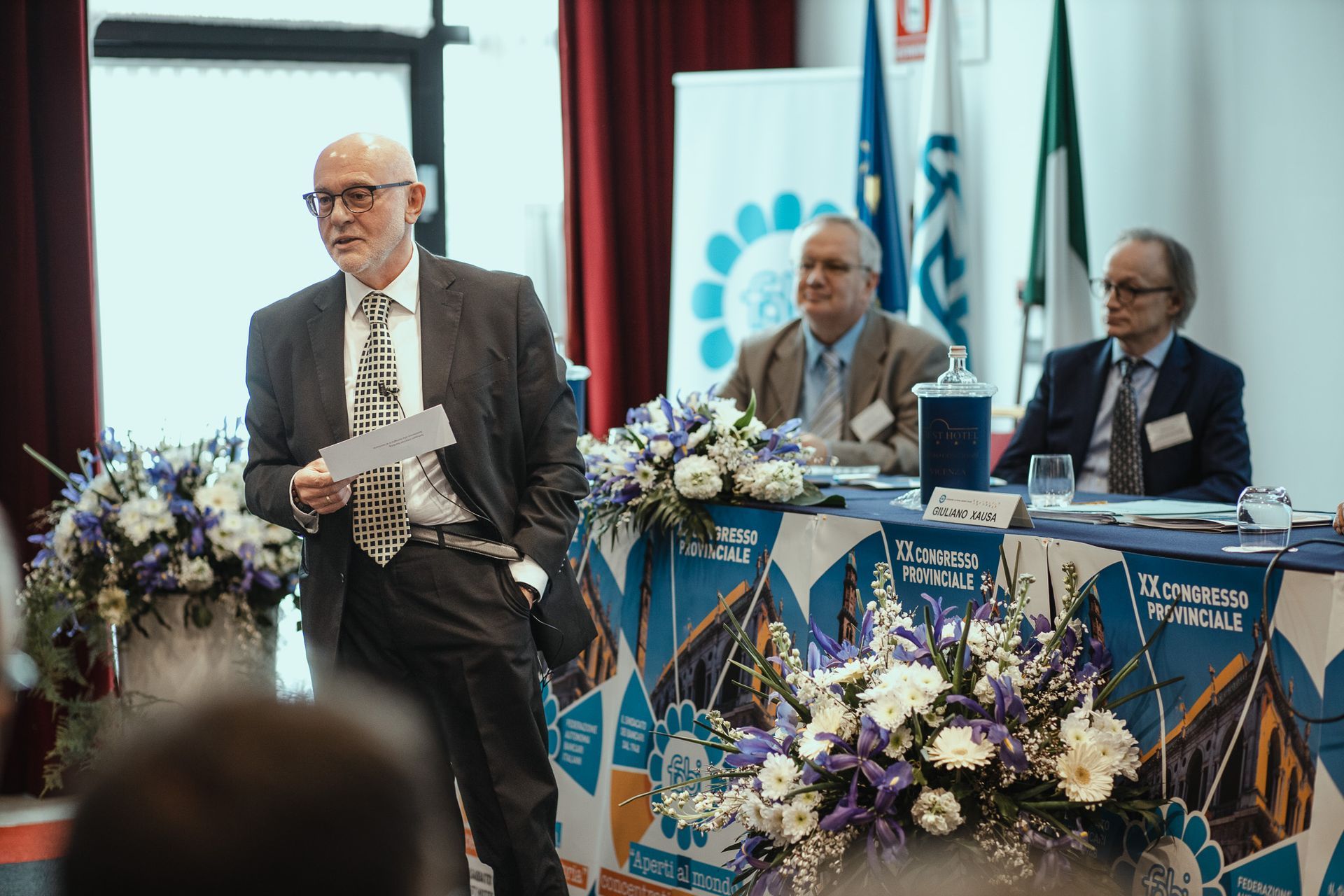 Un uomo in giacca e cravatta è in piedi davanti a un tavolo con dei fiori.
