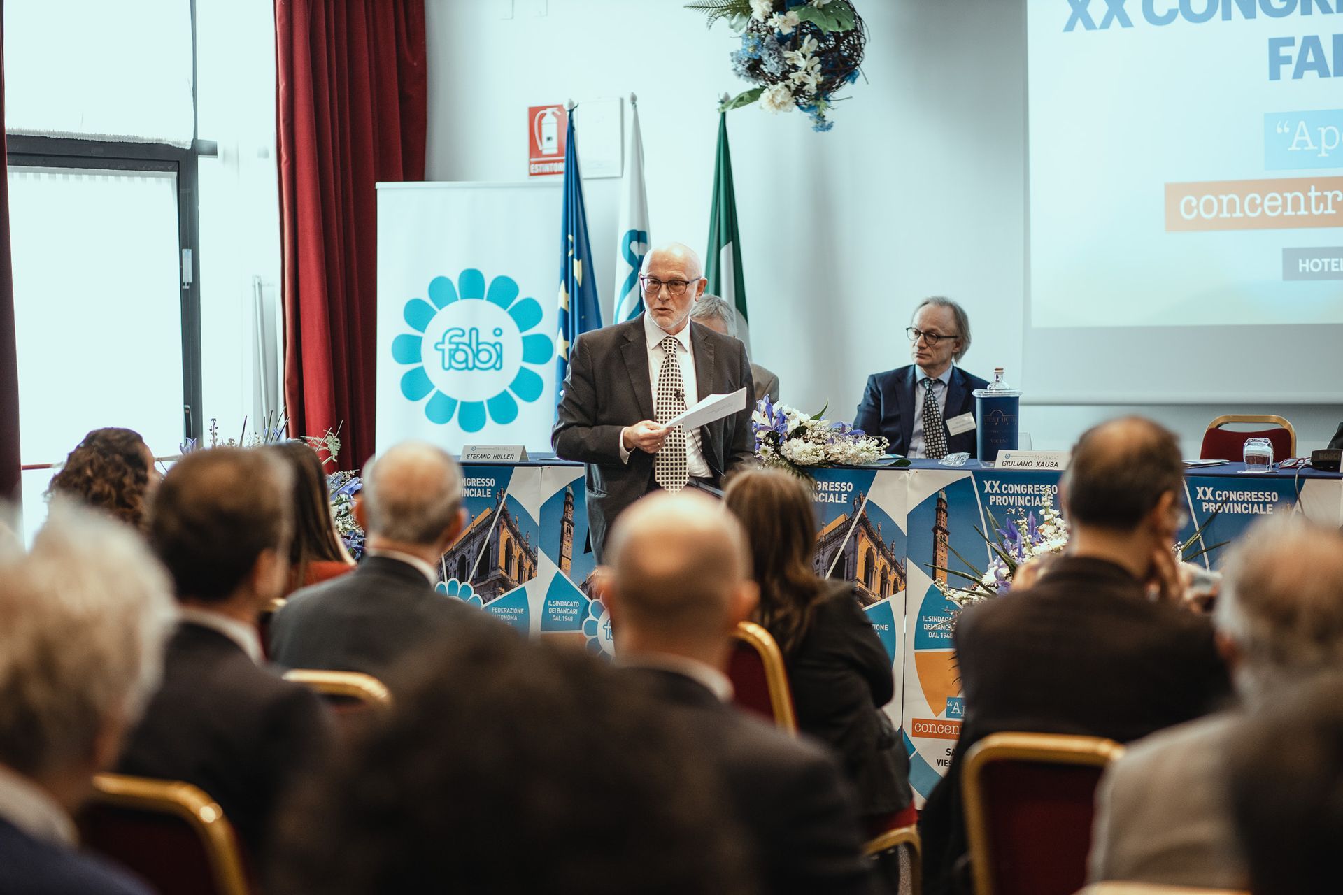 Un uomo tiene un discorso a un gruppo di persone in una sala conferenze.