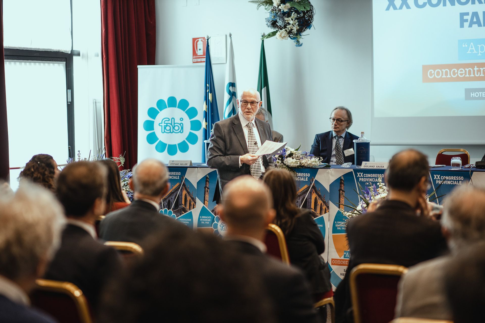 Un uomo tiene un discorso a un gruppo di persone in una sala conferenze.