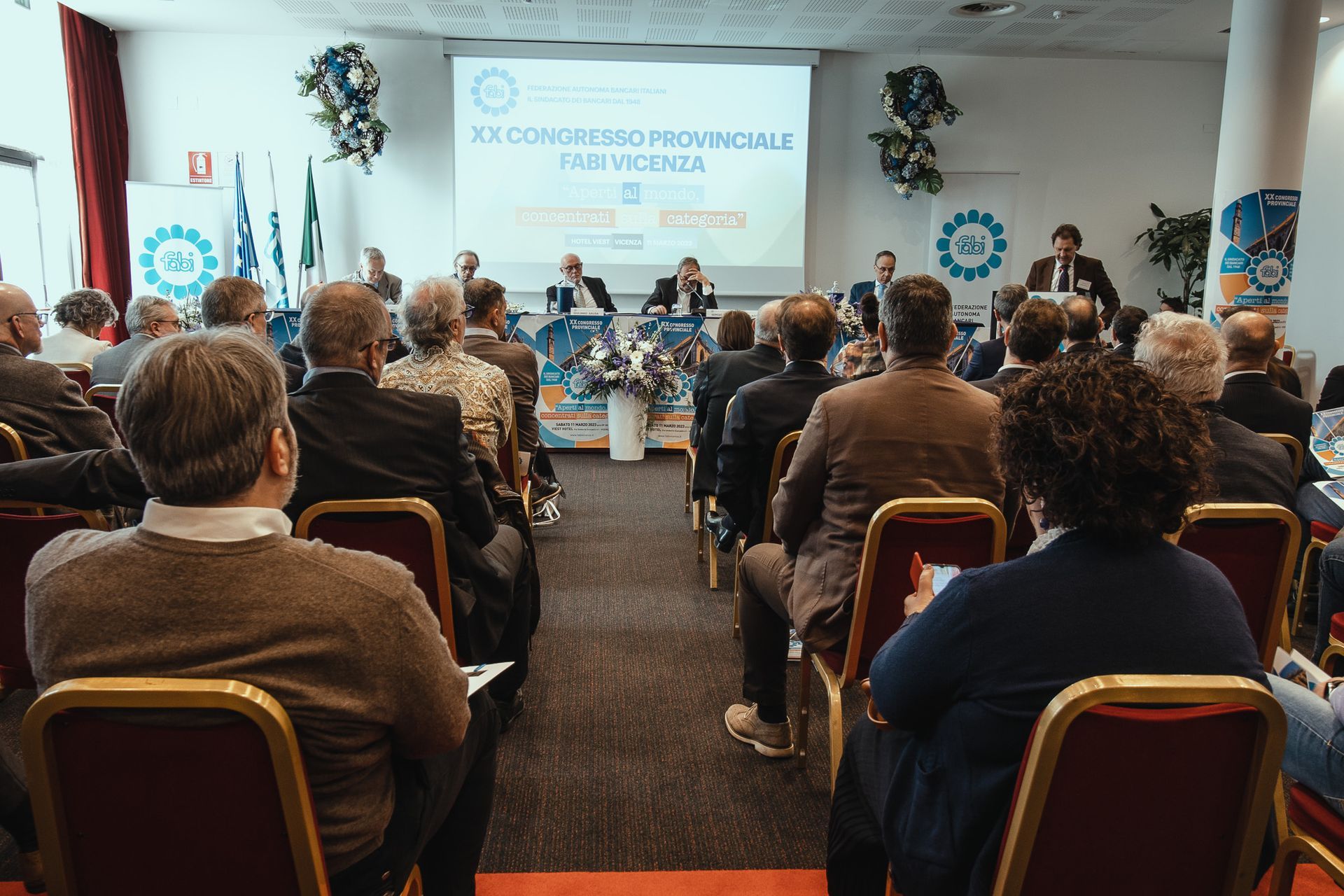 Un gruppo di persone è seduto in una sala conferenze e guarda una presentazione.