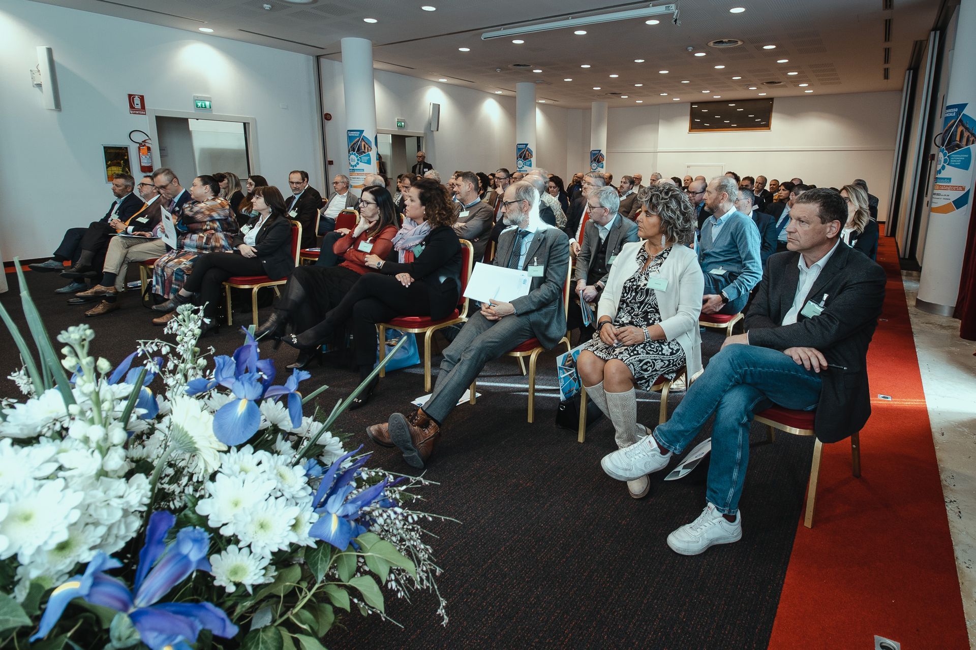 Un folto gruppo di persone è seduto sulle sedie in una sala conferenze.