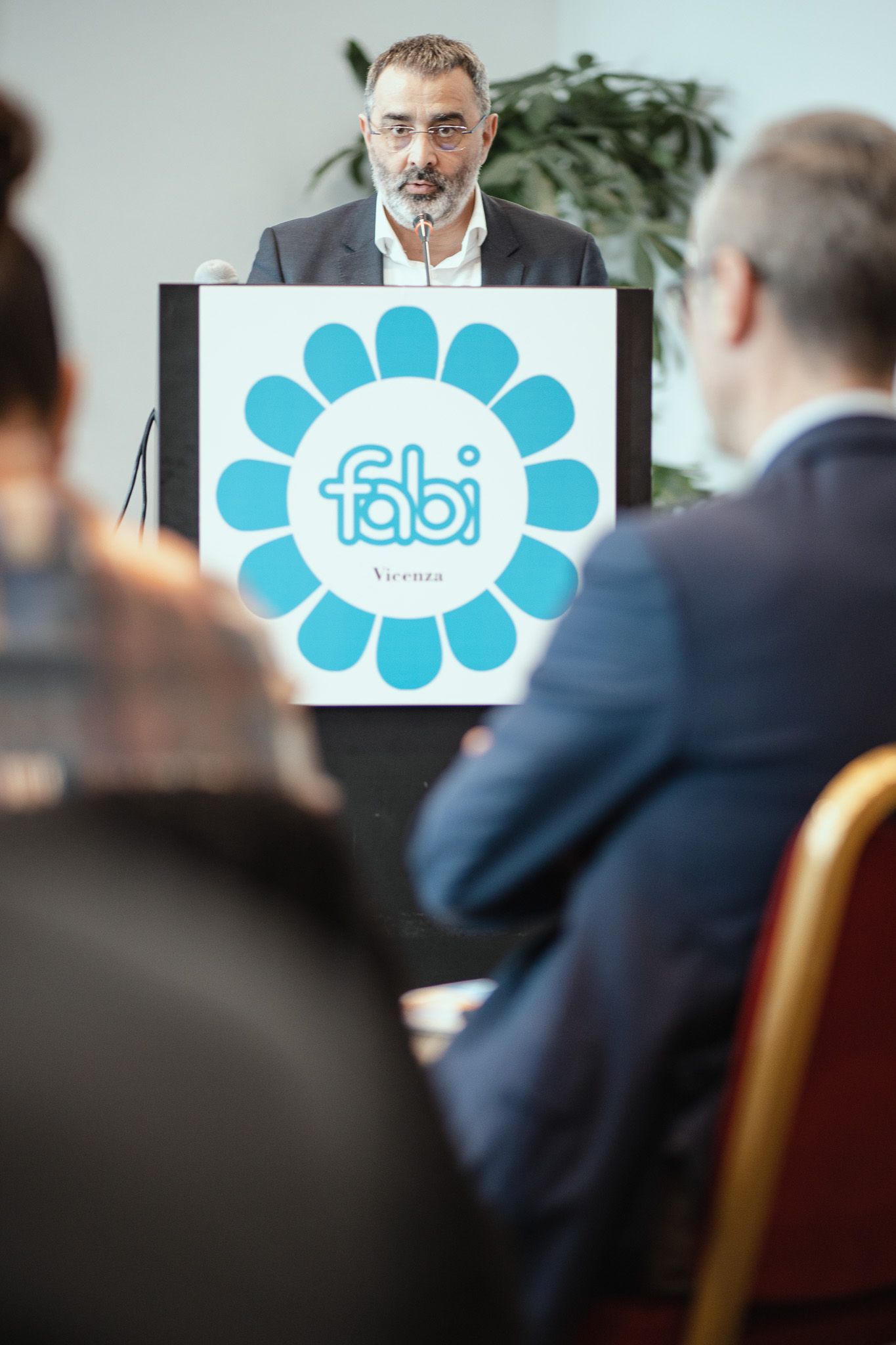 Un uomo tiene un discorso su un podio con sopra un favoloso logo