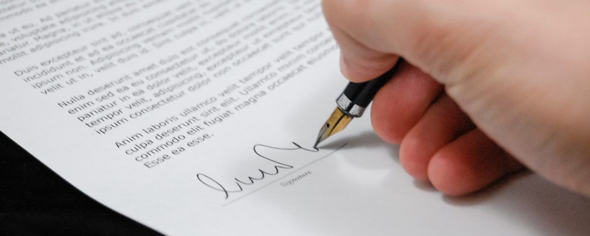 Una persona firma un documento con una penna stilografica.