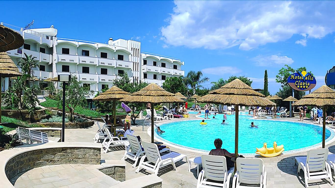 Una grande piscina circondata da sedie e ombrelloni di fronte ad un hotel.