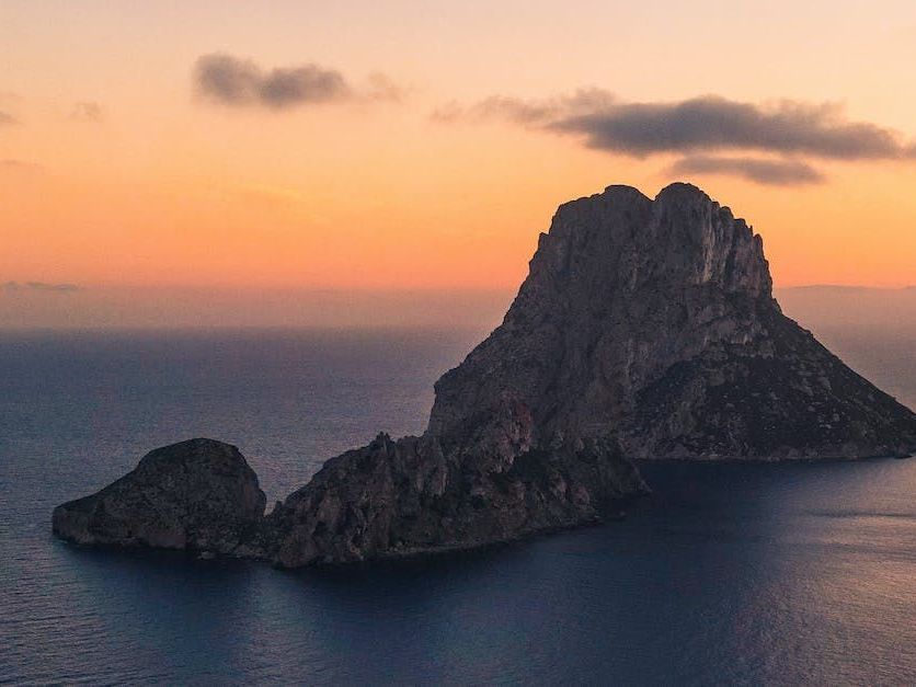 Una grande isola rocciosa in mezzo all’oceano al tramonto.