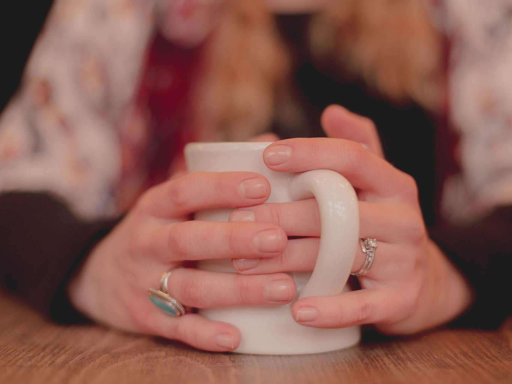 Una donna tiene tra le mani una tazza di caffè.