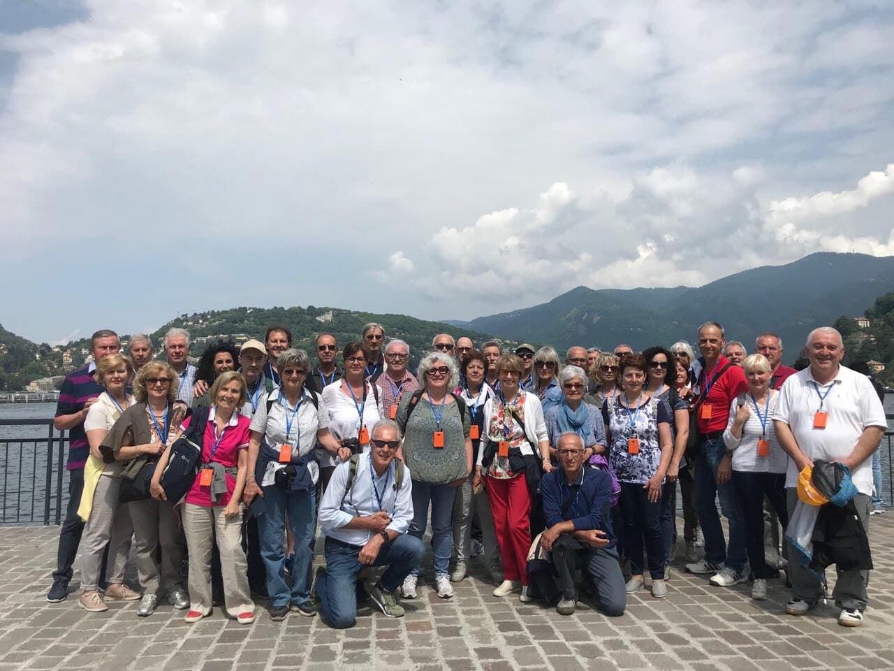 Un folto gruppo di persone posa per una foto davanti ad un lago.