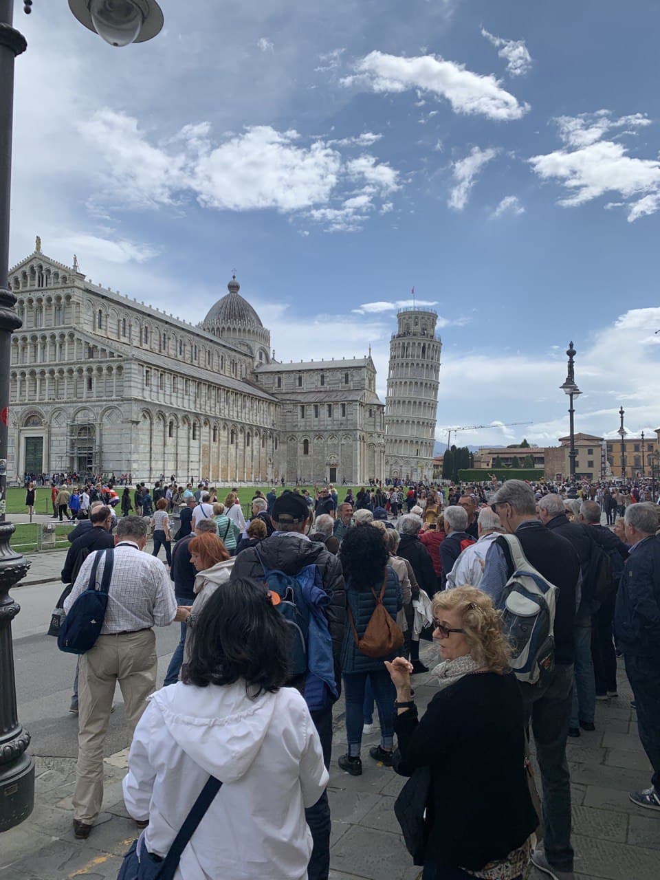 Un folto gruppo di persone si trova davanti a un grande edificio.