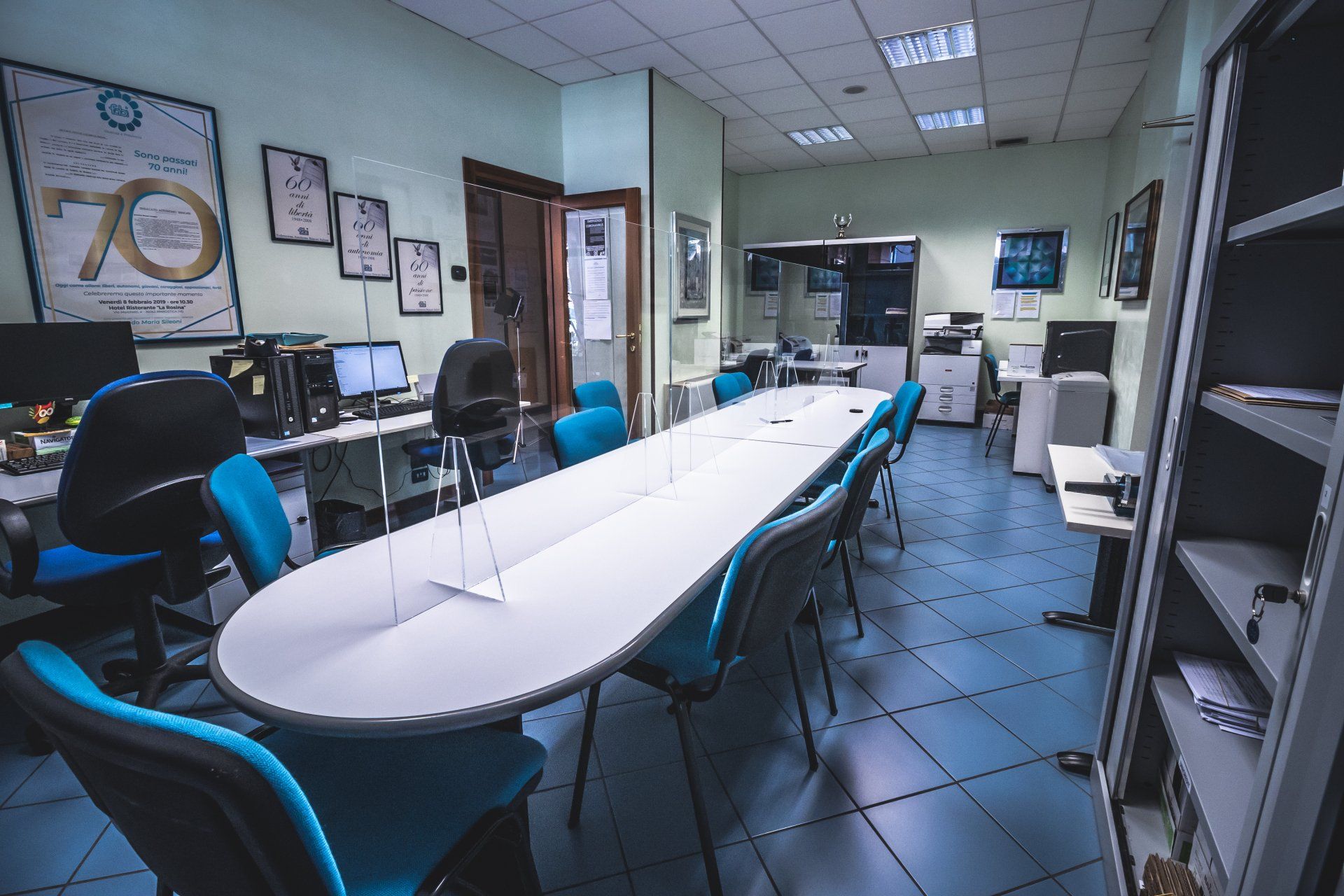 Una sala conferenze con un lungo tavolo e sedie blu