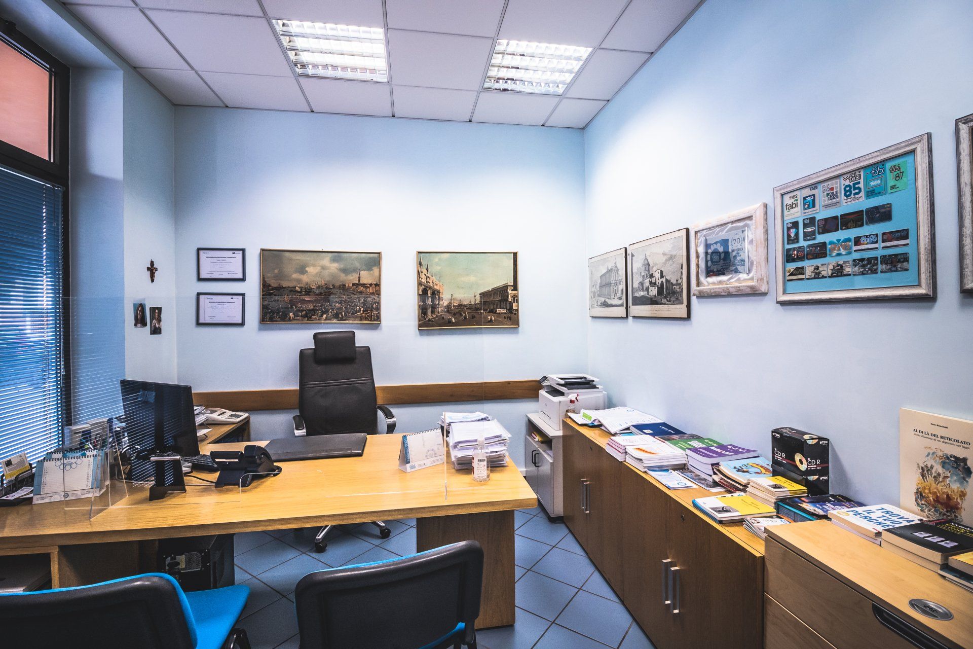 Una stanza con scrivania, sedie e quadri alle pareti