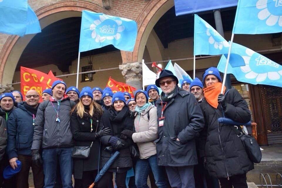 Un gruppo di persone è in piedi davanti a un edificio con delle bandiere.