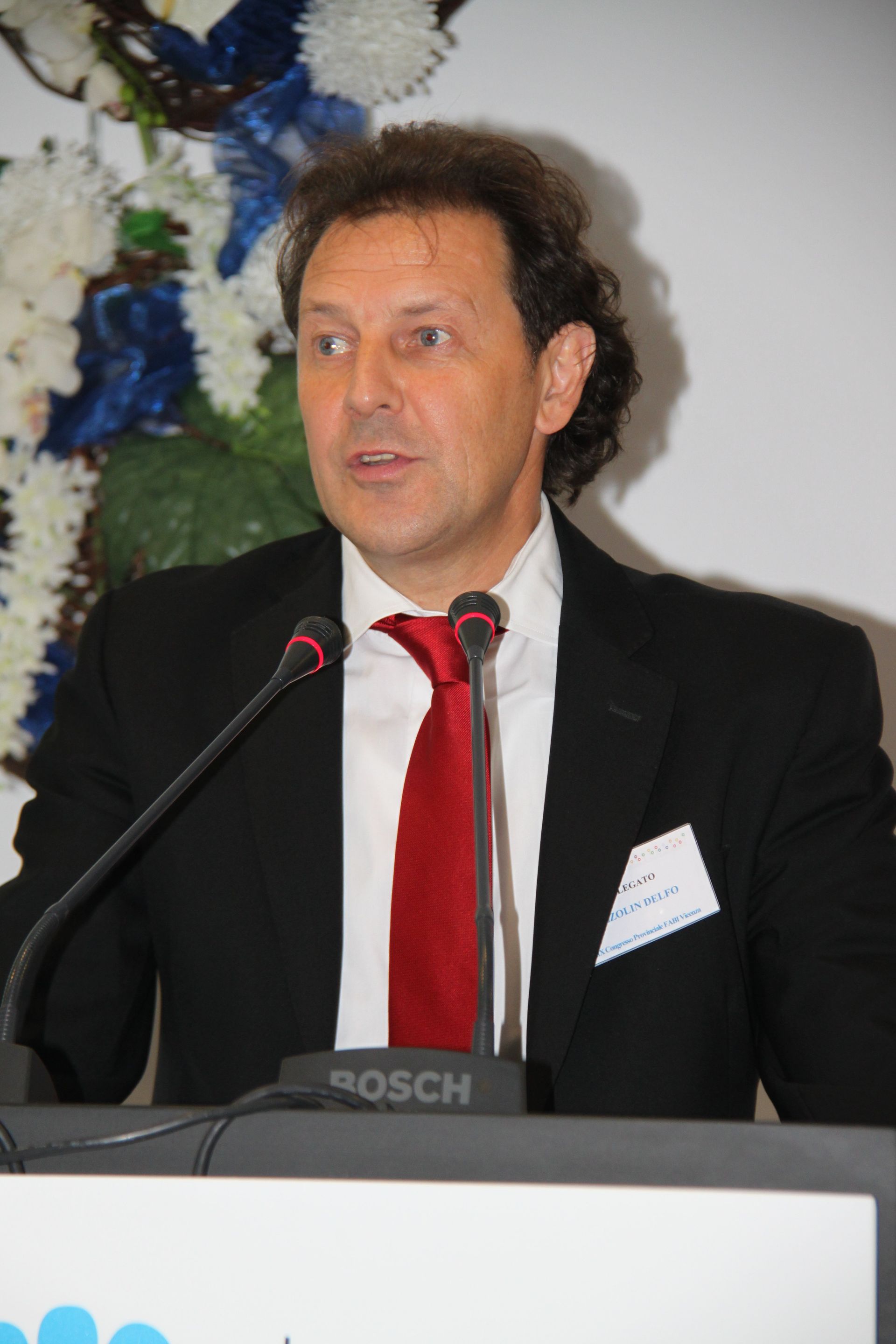 Un uomo in giacca e cravatta parla al microfono Bosch