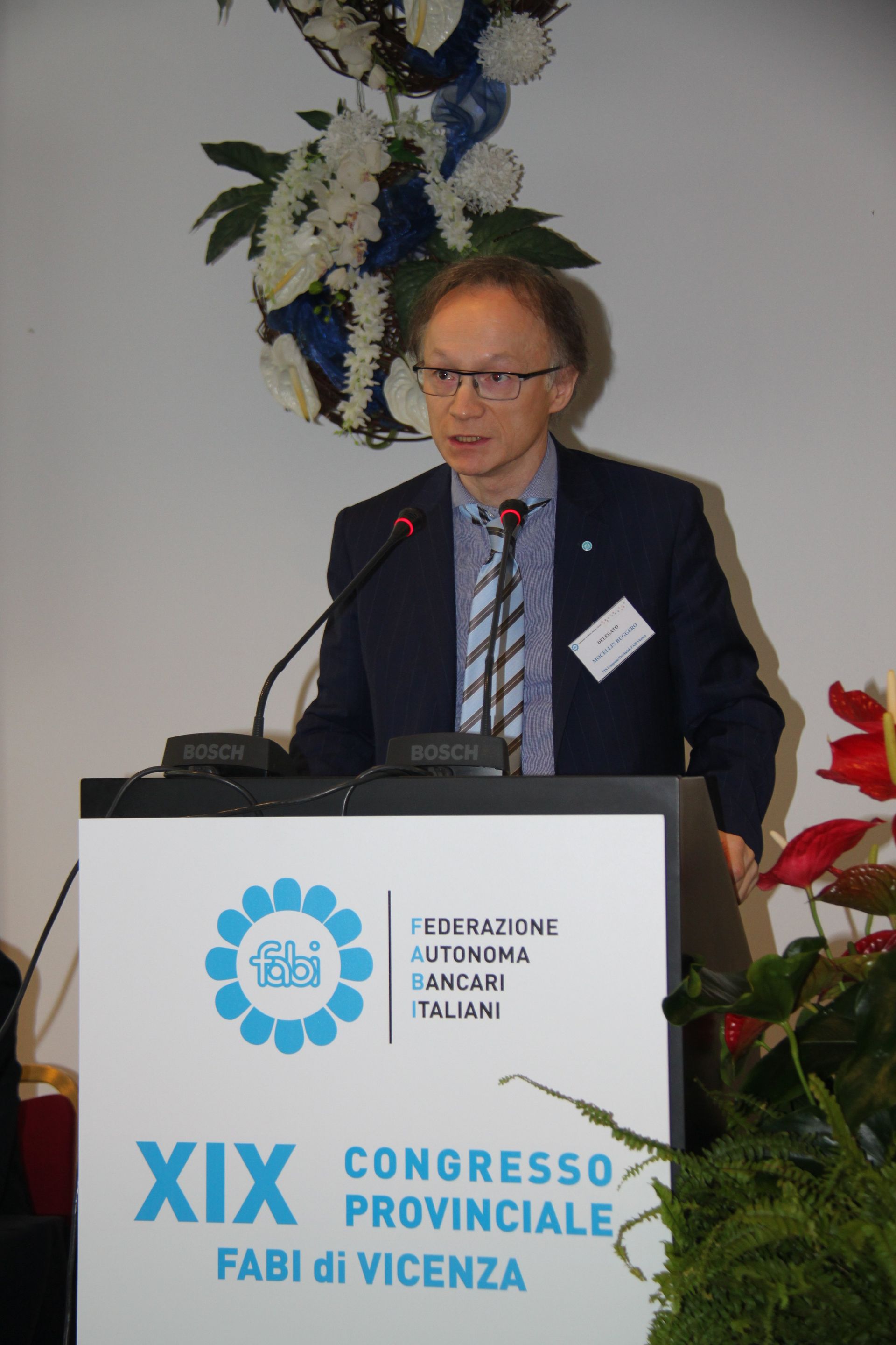 Un uomo in giacca e cravatta è in piedi su un podio e tiene un discorso.