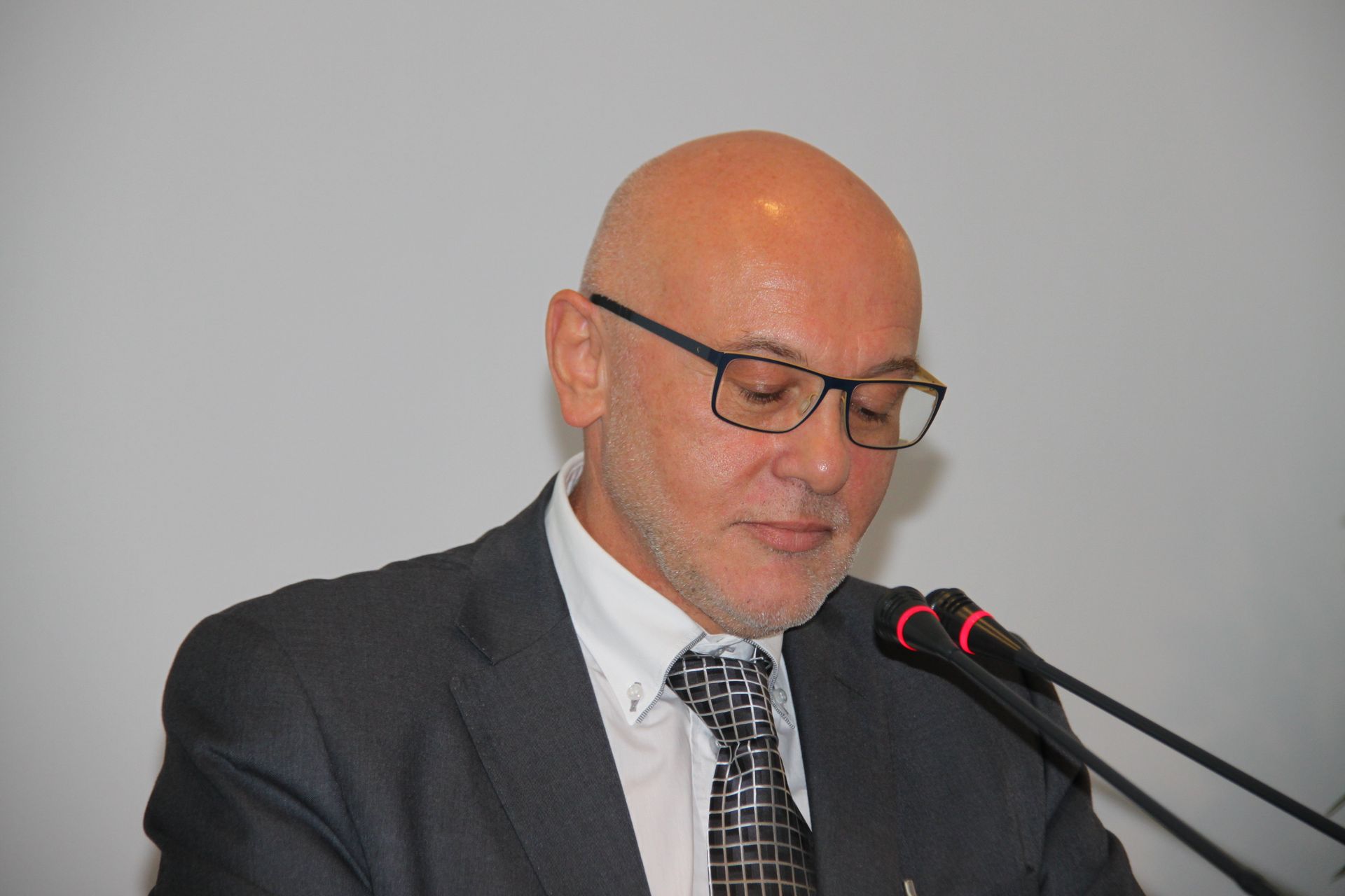 Un uomo in giacca e cravatta parla al microfono.