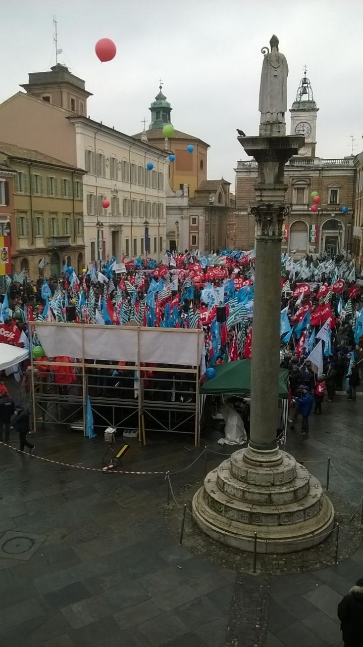 Una grande folla di persone è radunata in una piazza cittadina