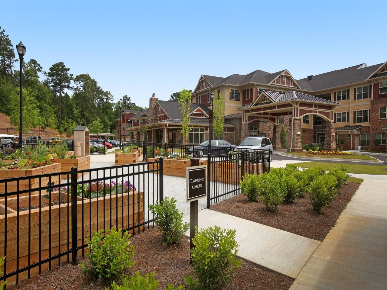 Exterior view of an apartment community with a gated garden and building entrance.