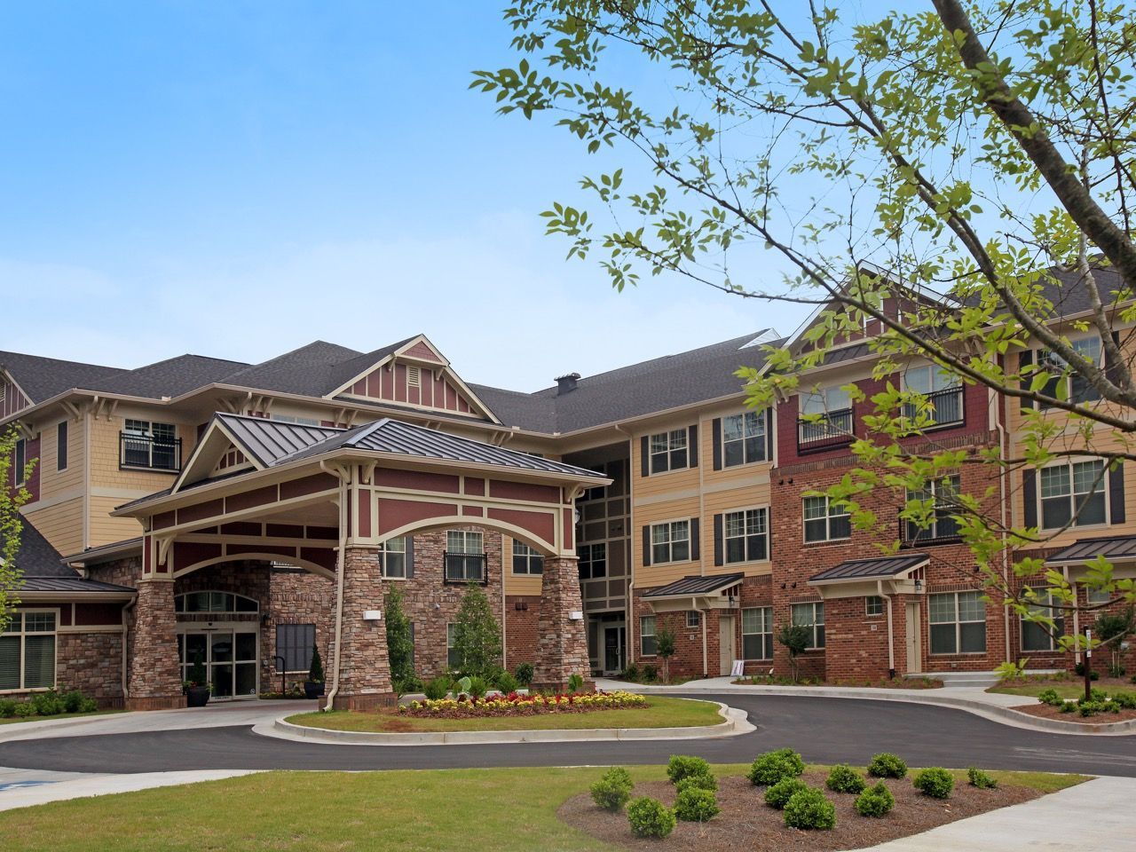 Exterior view of a multifamily apartment complex with a covered entrance and landscaped grounds.