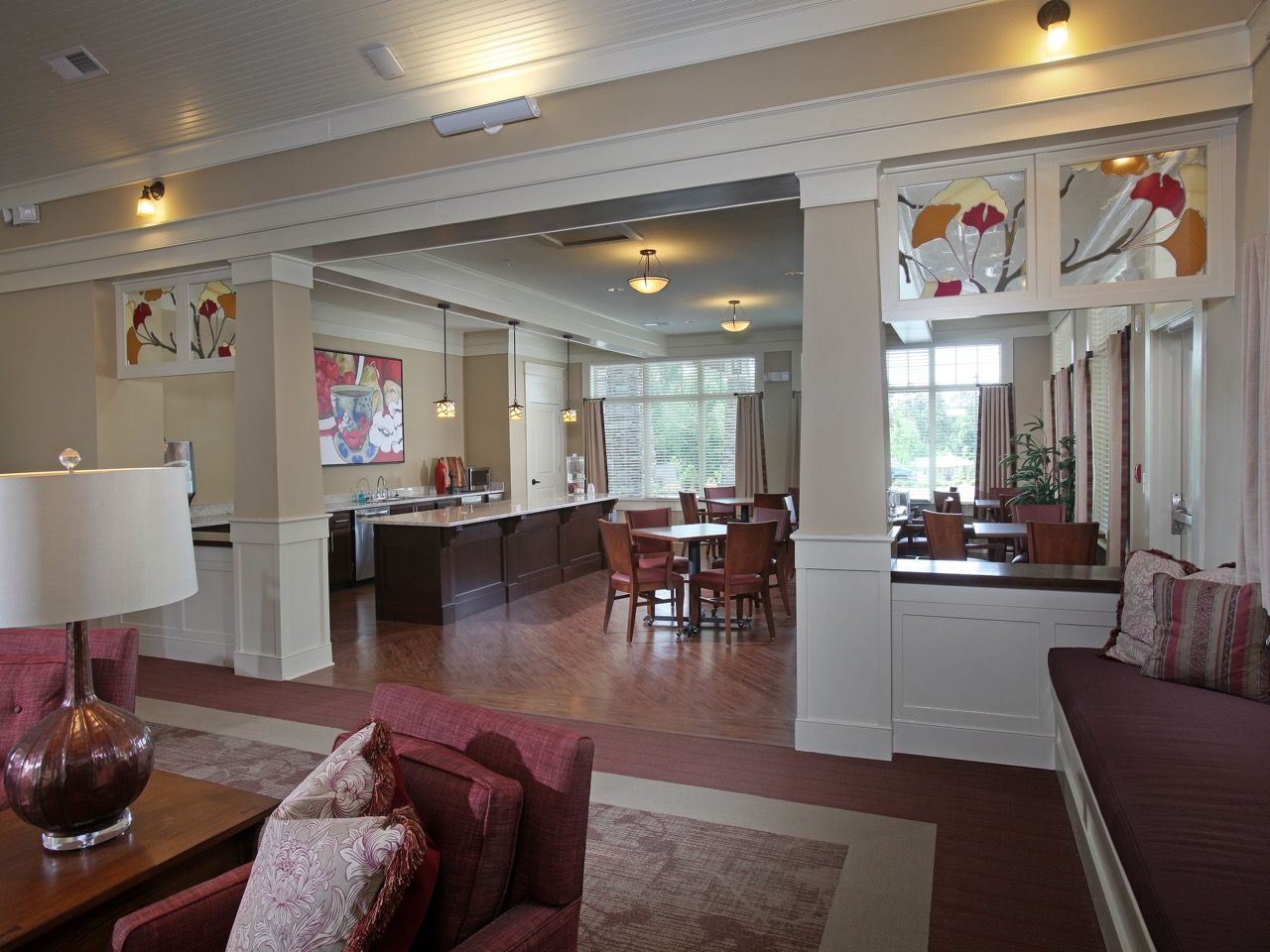 Indoor community lounge with couches, tables, and a kitchenette in a residential building.