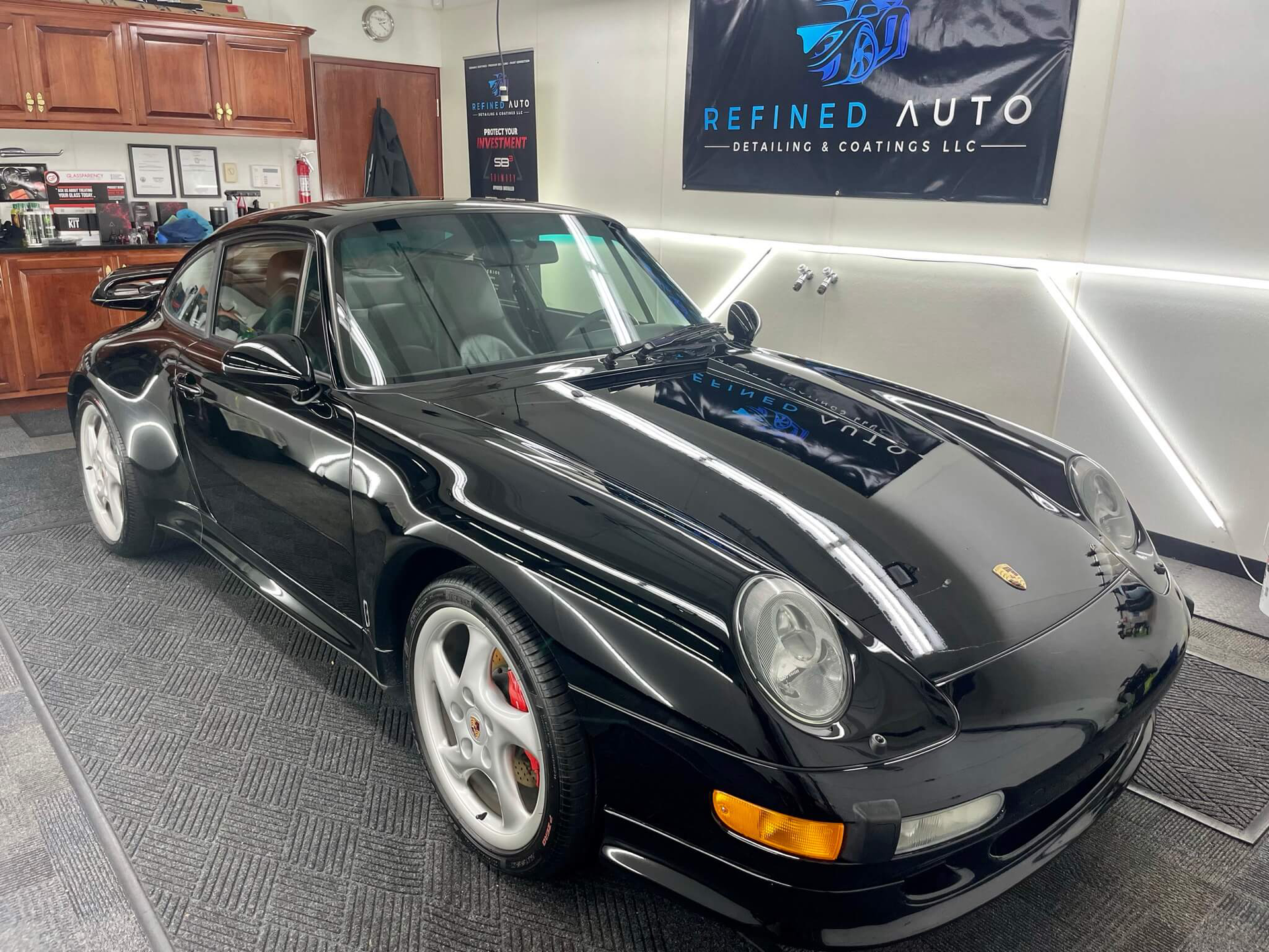 A person wearing blue gloves is polishing the hood of a white car.