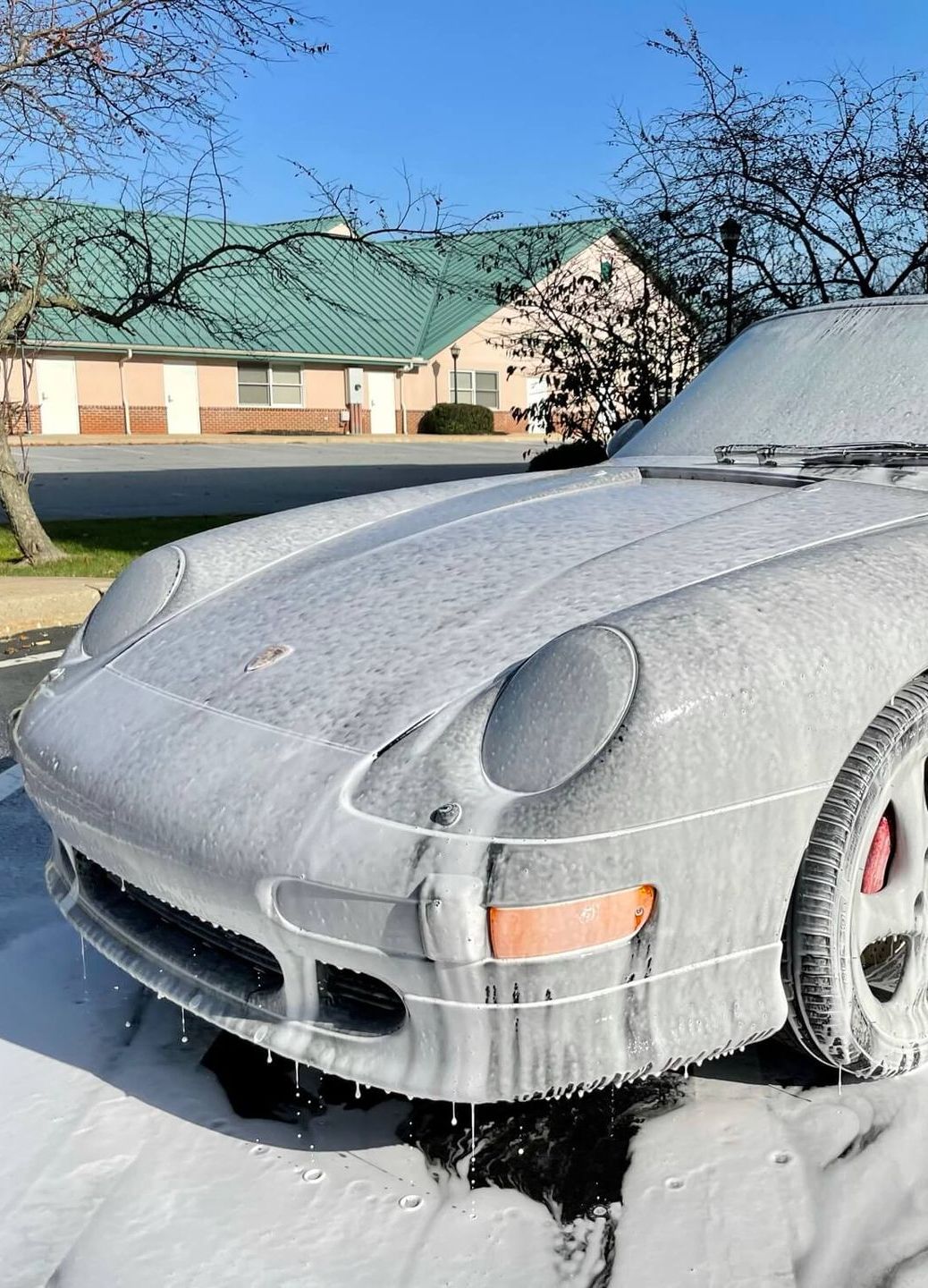 A car is covered in foam in front of a house