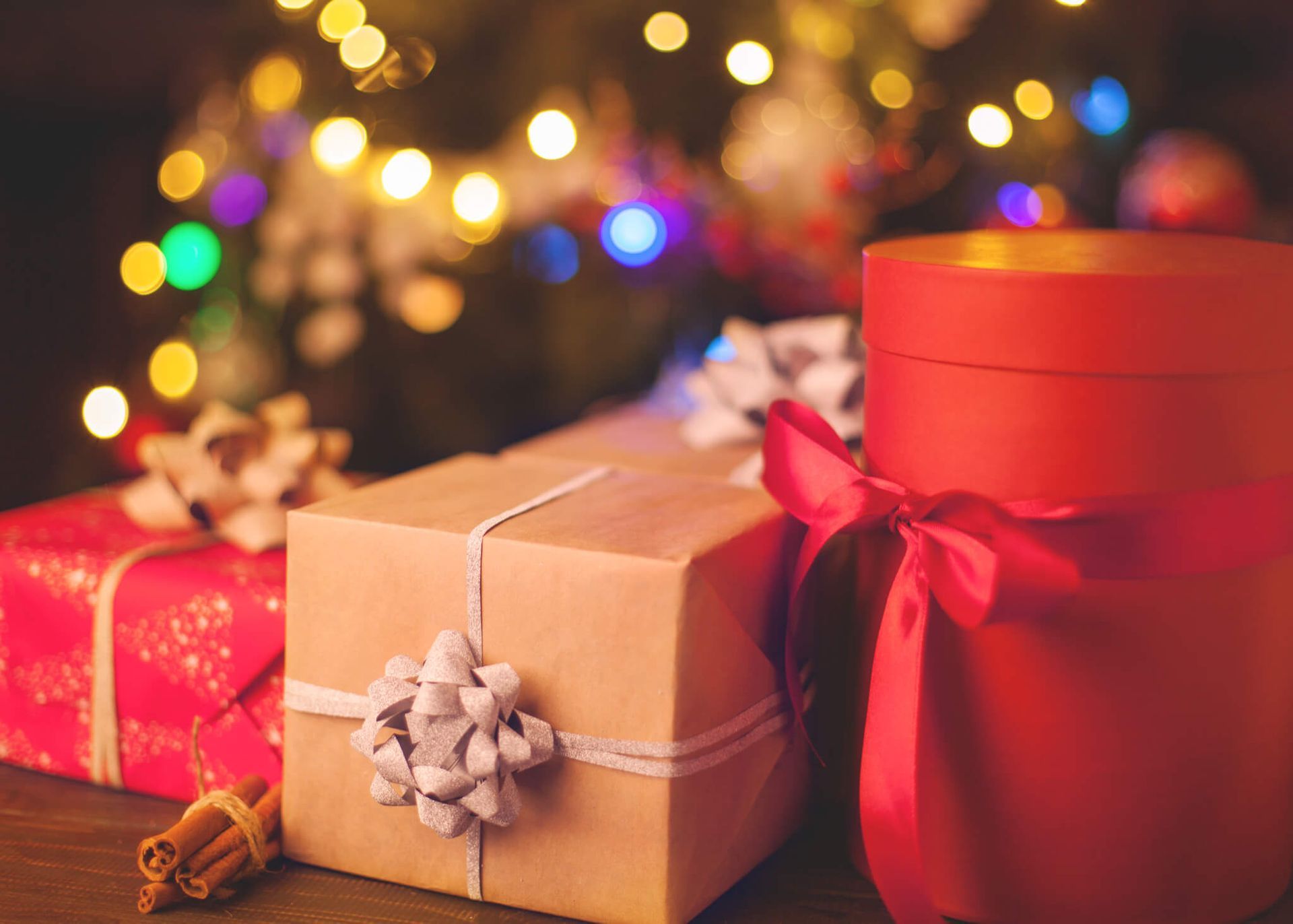 Christmas presents are sitting on a wooden table in front of a christmas tree.