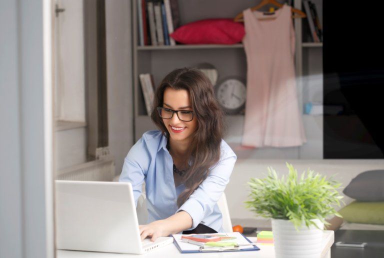 A woman is sitting at a desk using a laptop computer.