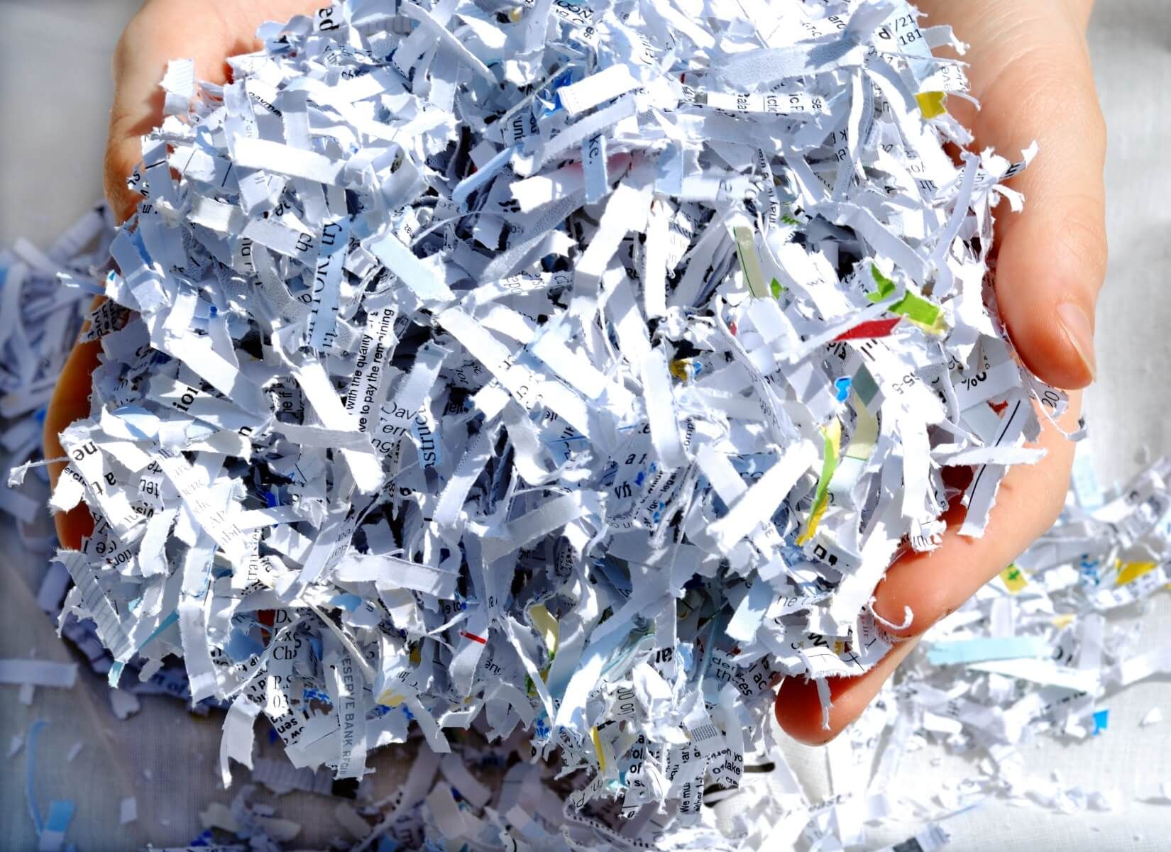 A person is holding a pile of shredded paper in their hands.