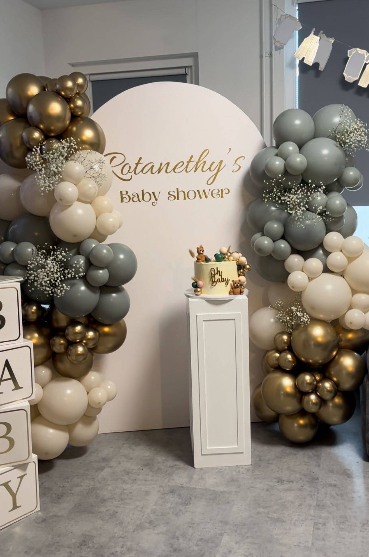 Een babyshower met ballonnen en een taart op een voetstuk.