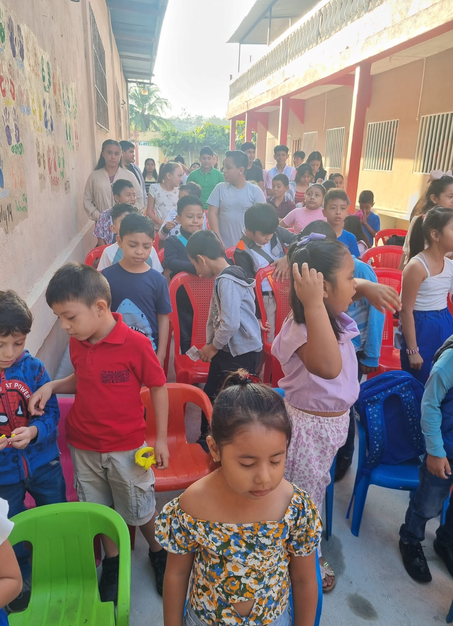 a group of children are sitting in chairs outside of a building .