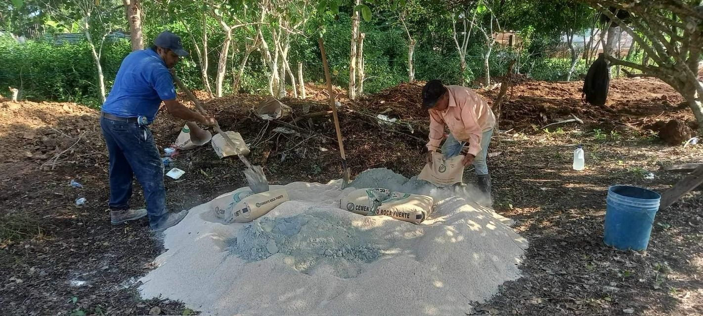 two men are working on a pile of dirt in the woods .