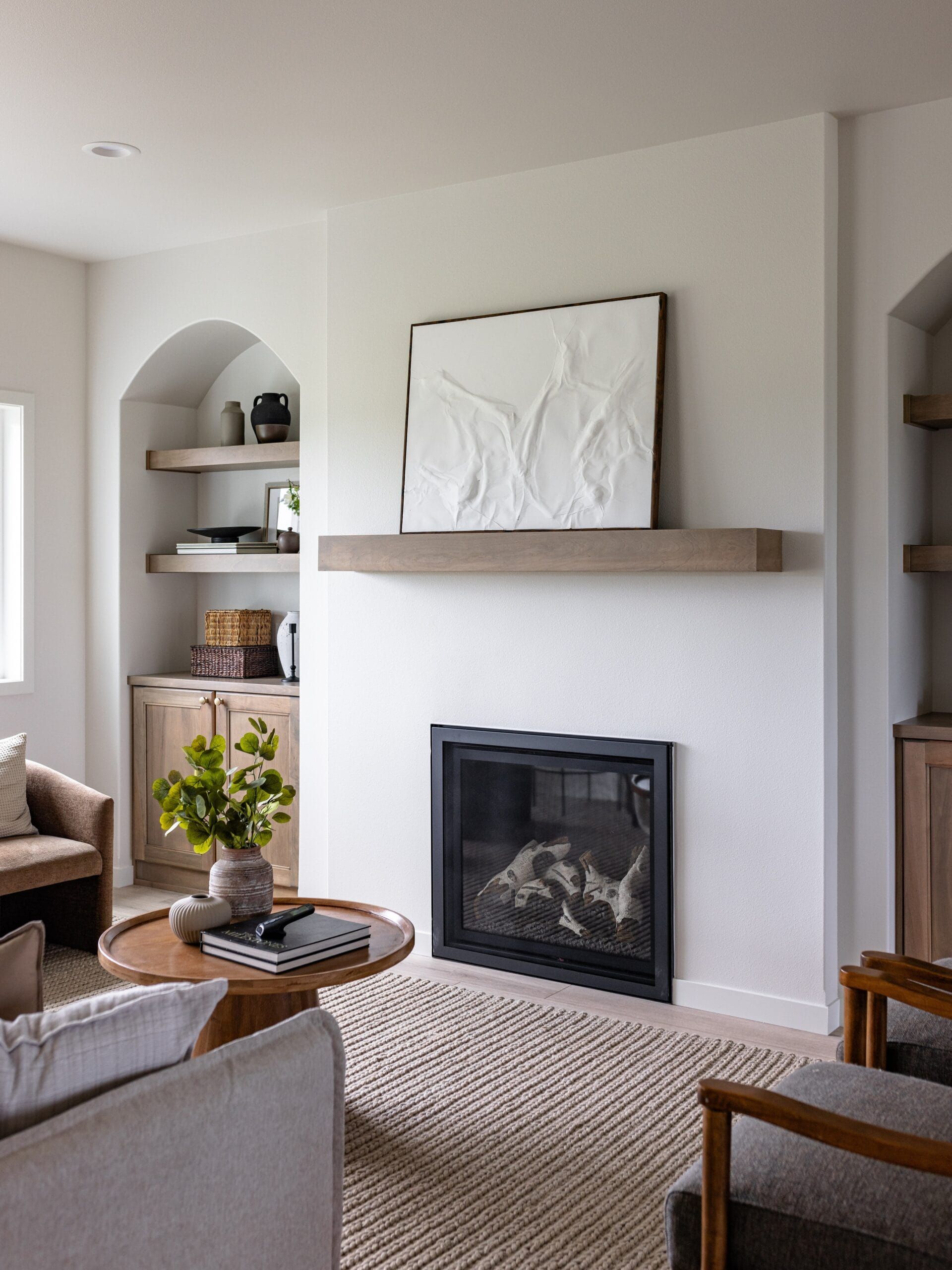 Living room with fireplace, built-in shelves, wood mantel, neutral tones, and modern decor.