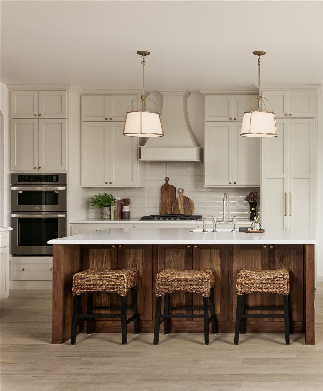 Kitchen with island seating, white cabinets, and wood accents; pendant lights hang above.