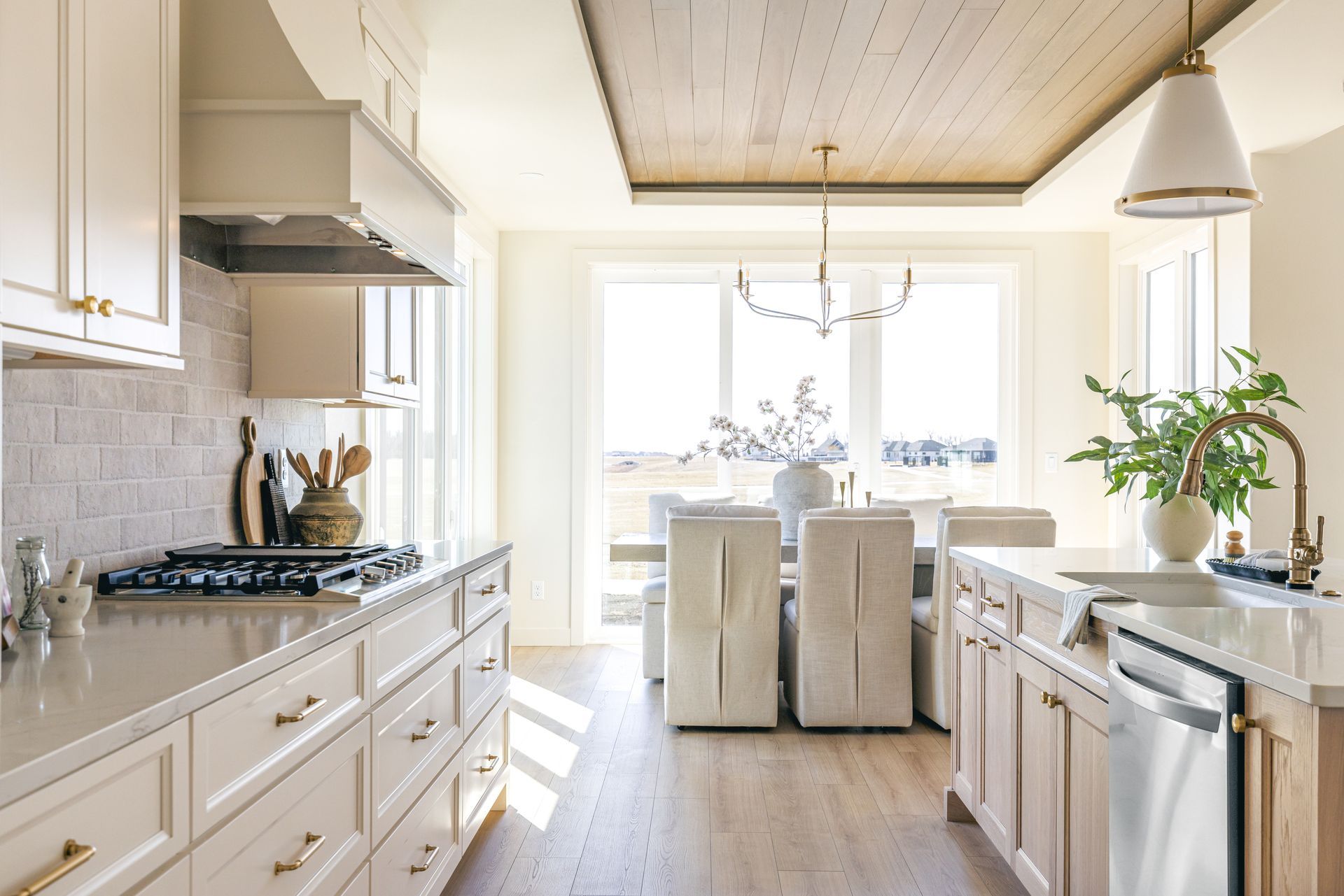 Elegant kitchen with light-colored cabinets, white countertops, and wood ceiling. 