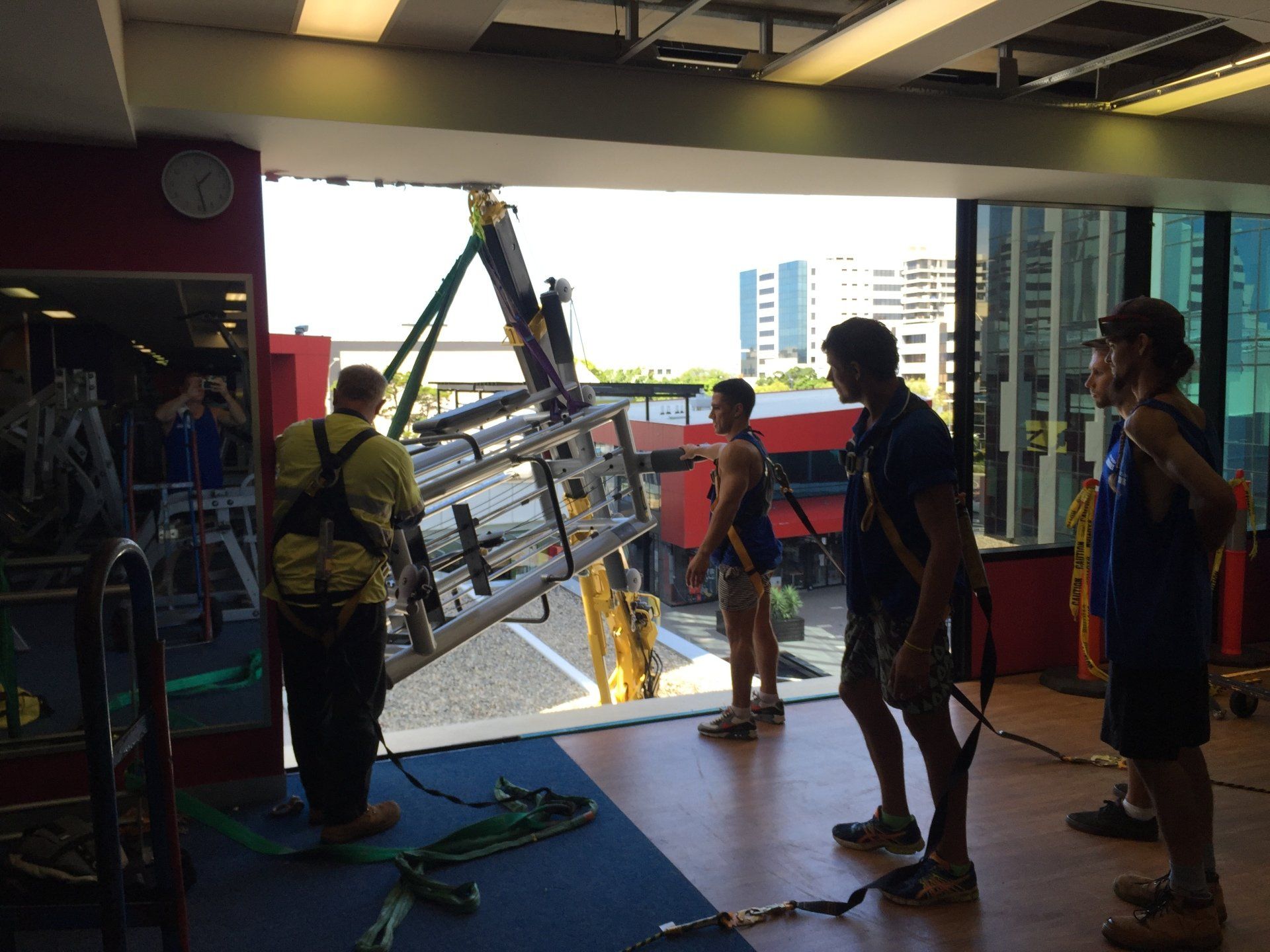 A group of men are lifting a ladder in a gym.