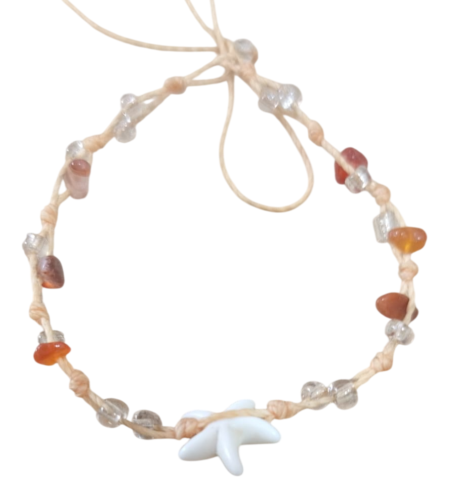 Pulsera de cuentas con piedras transparentes y ámbar y un dije de estrella de mar blanca en un cordón beige.