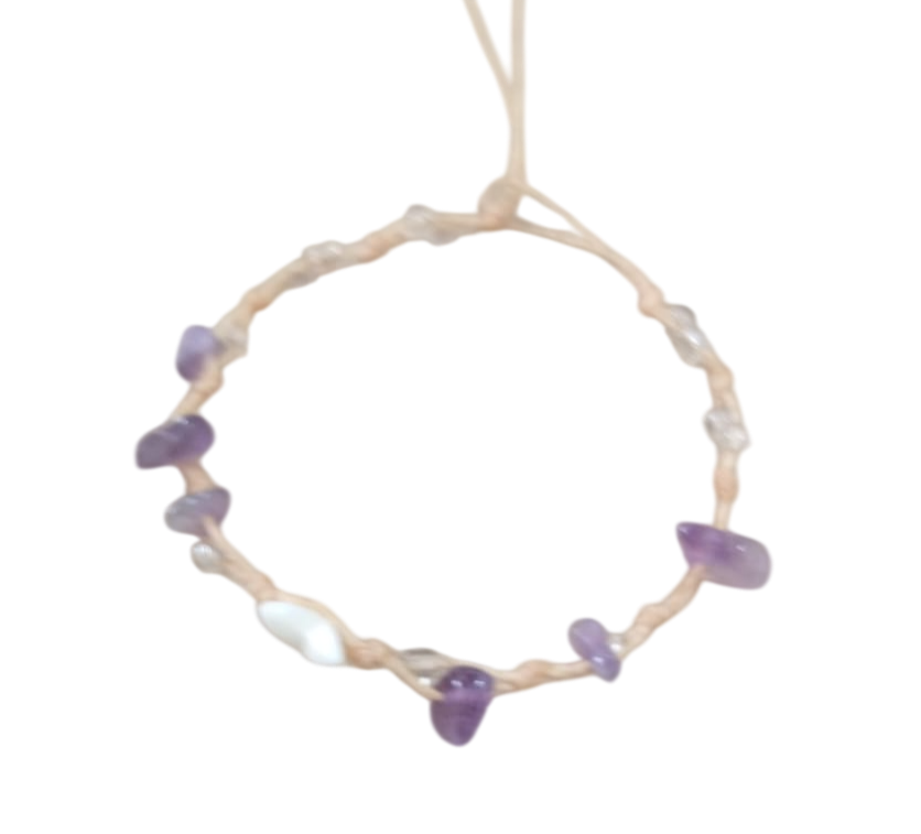 Pulsera delicada de cuentas con piedras moradas y blancas en un cordón fino, mostrada sobre un fondo blanco.