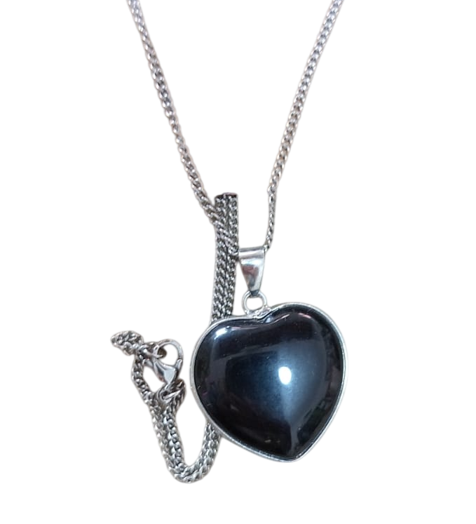 Collar de plata con un colgante negro en forma de corazón y un detalle de cadena colgante.