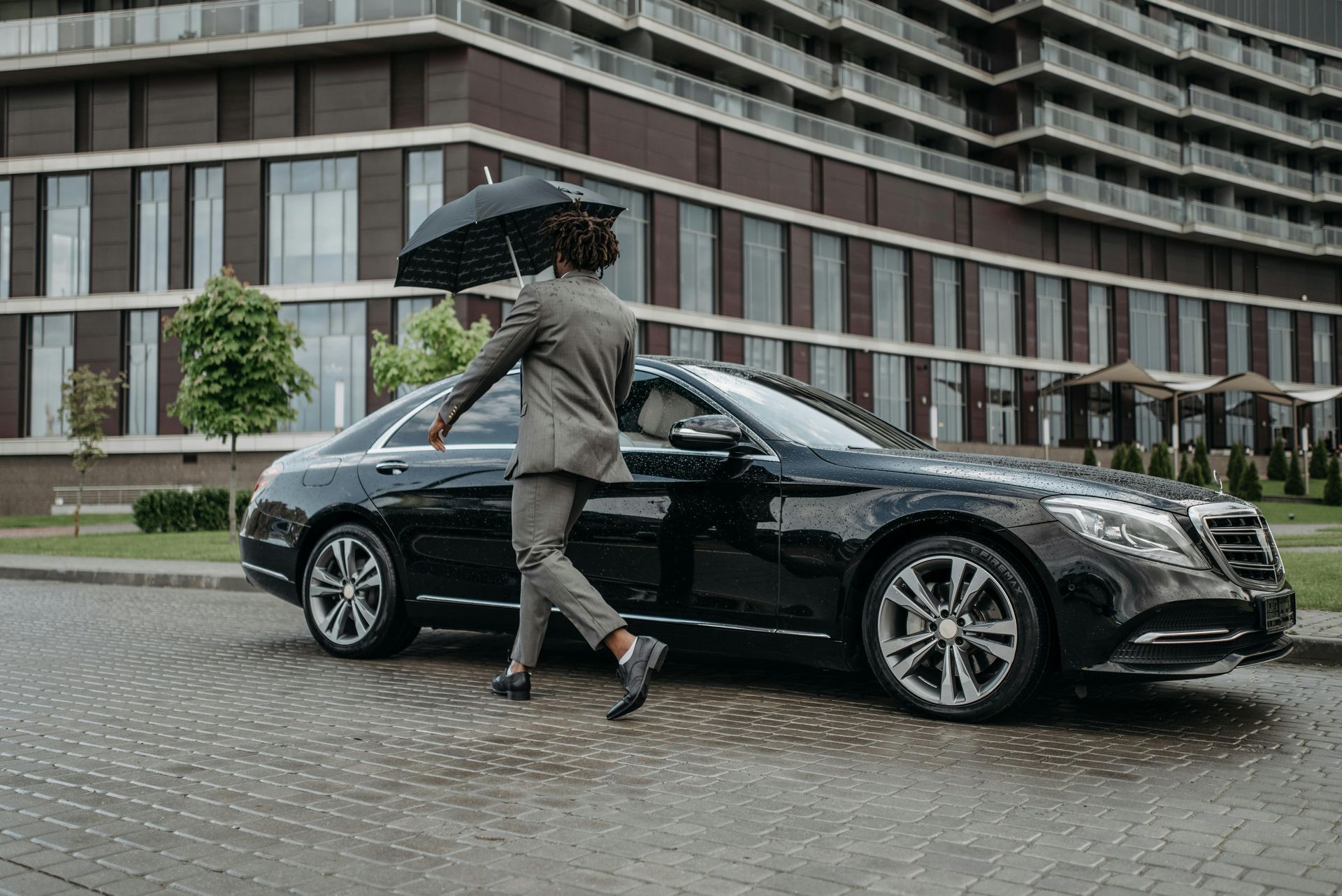 Chauffeur opening the door beside a luxury black car for executive transportation service