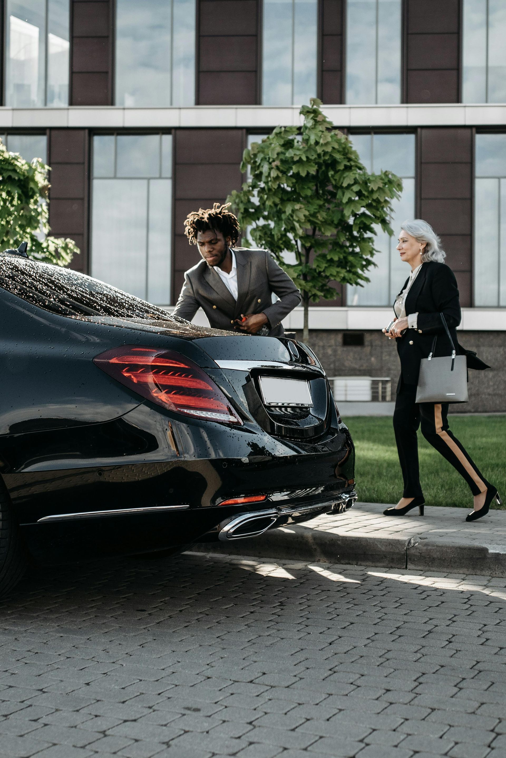 Chauffeur standing beside black luxury car, showing the benefits of booking