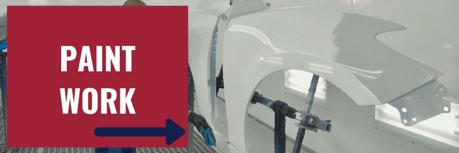 A car fender being painted in a shop, with a red sign to the left that reads 