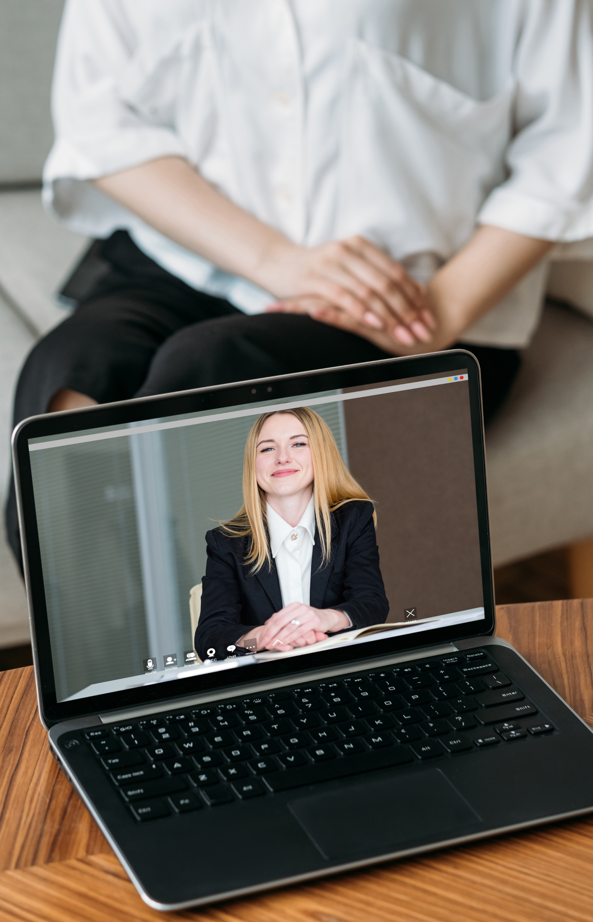 A woman is sitting on a couch watching a video on a laptop.