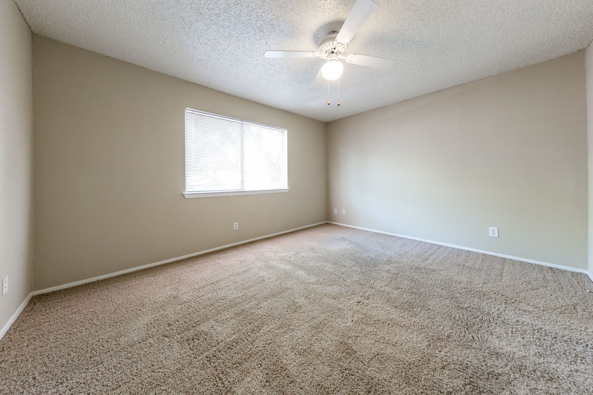 An empty bedroom with a ceiling fan and a window at SoCo on the Lake in Austin, TX.