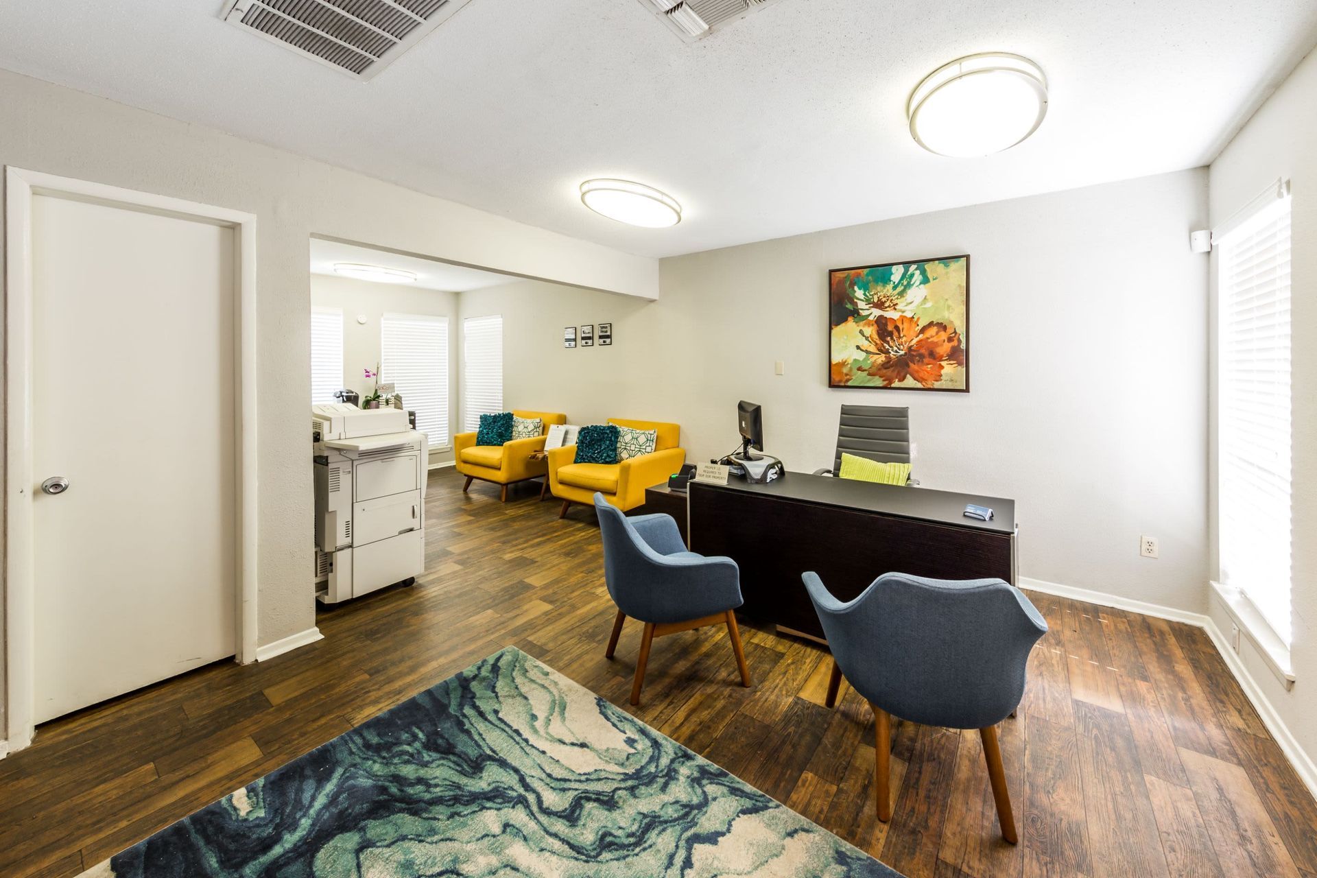 Apartment leasing office with a desk, chairs, printer, and a rug at SoCo on the Lake in Austin, TX.