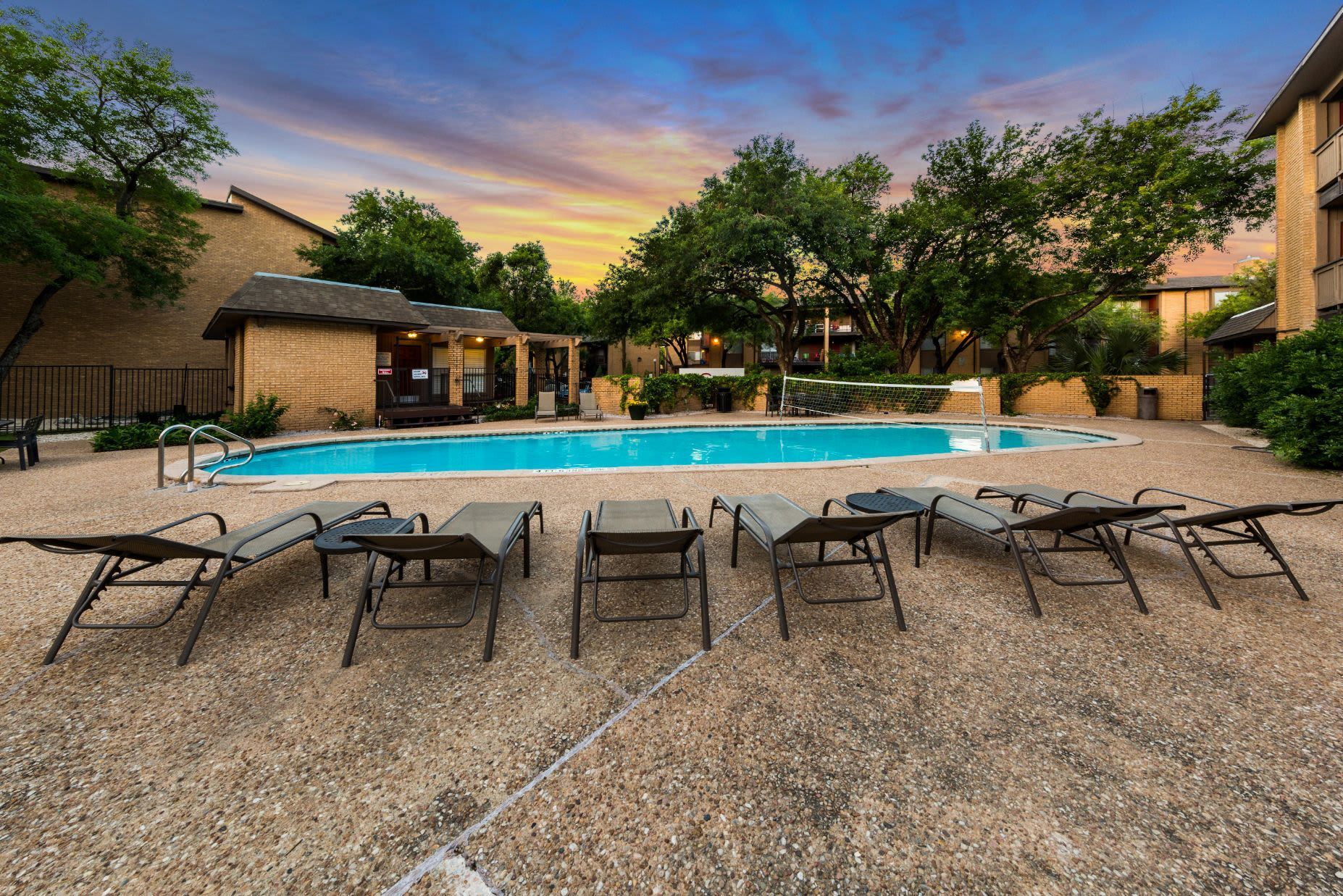 A row of lounge chairs sitting next to a luxury swimming pool at SoCo on the Lake in Austin, TX.