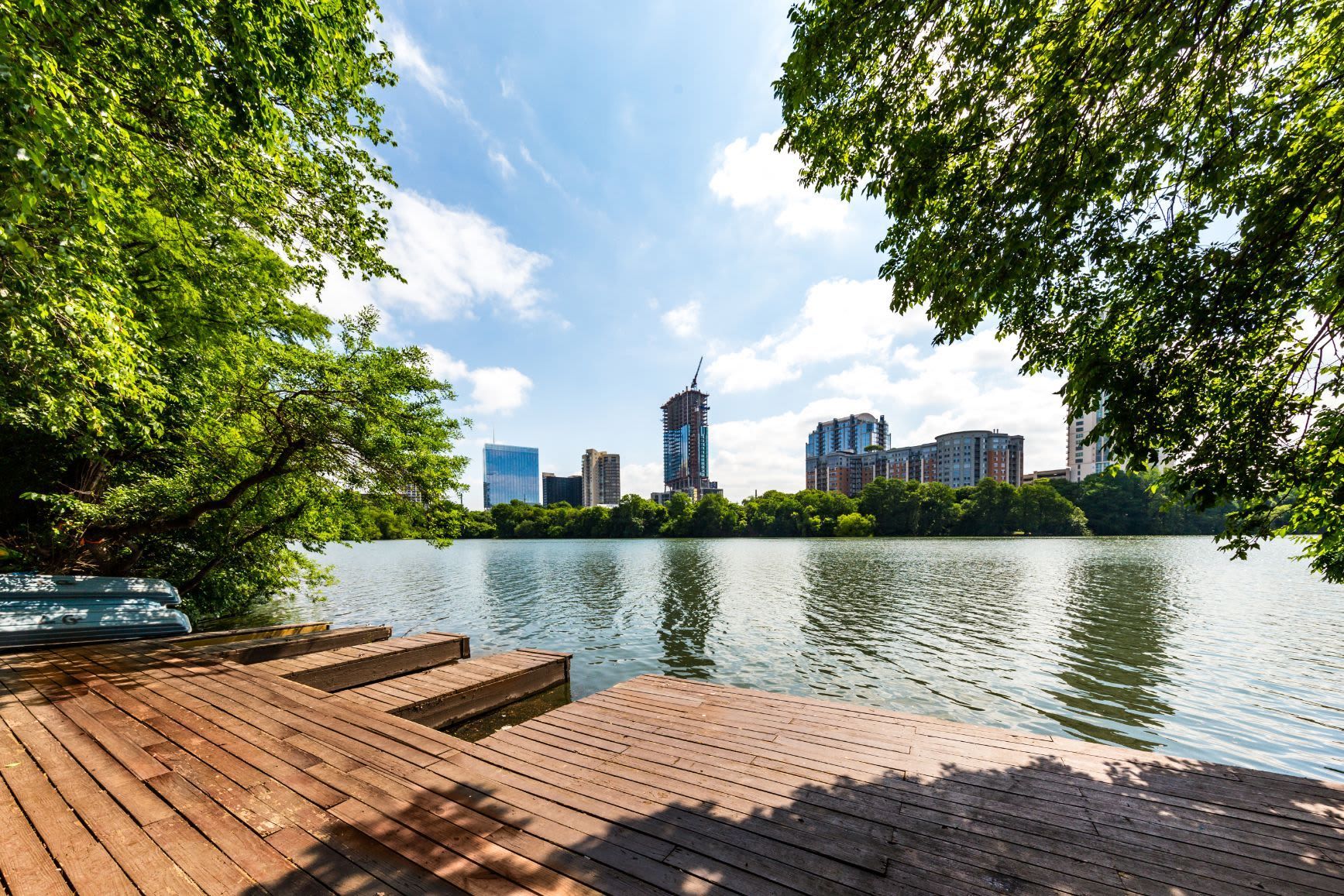 A wooden dock overlooking a lake with a city skyline in the background