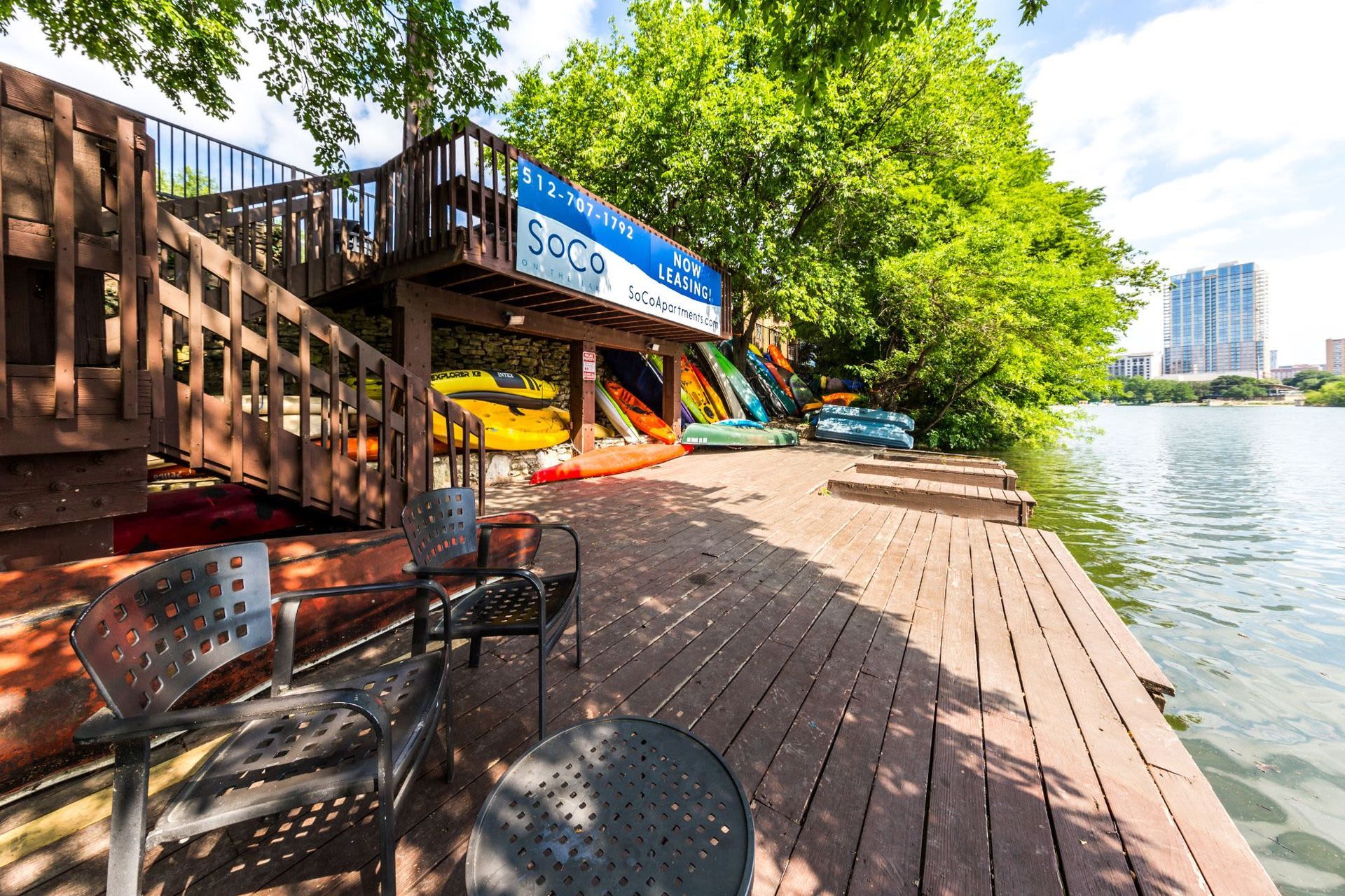 A wooden deck with chairs and a table next to a body of water.