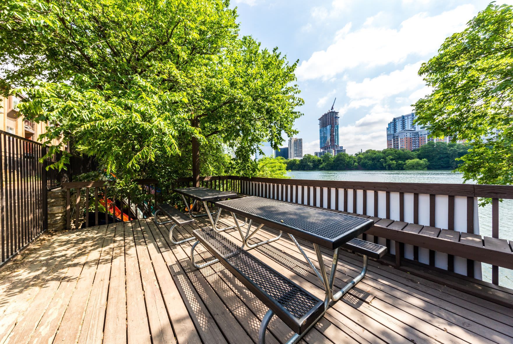 A wooden deck with a picnic table and benches overlooking a lake at SoCo on the Lake in Austin, TX.